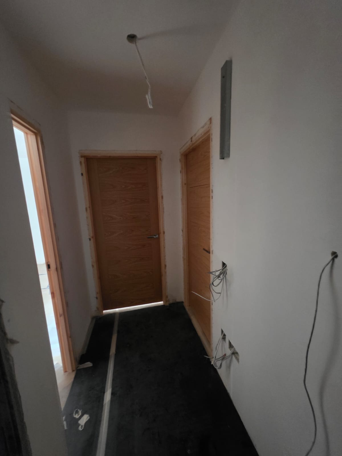 Hallway with newly hung oak internal doors, chrome handles and floor protection in Southend-on-Sea by DWELLUX