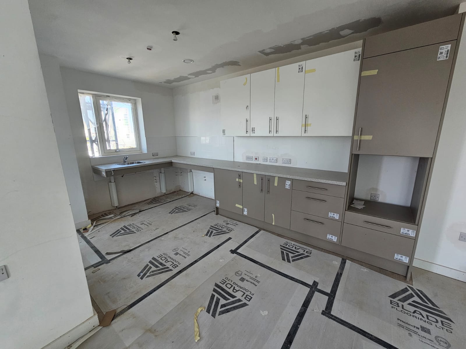 Accessible wheelchair-friendly social housing kitchen installation with low worktops and floor protection in Surrey Quays