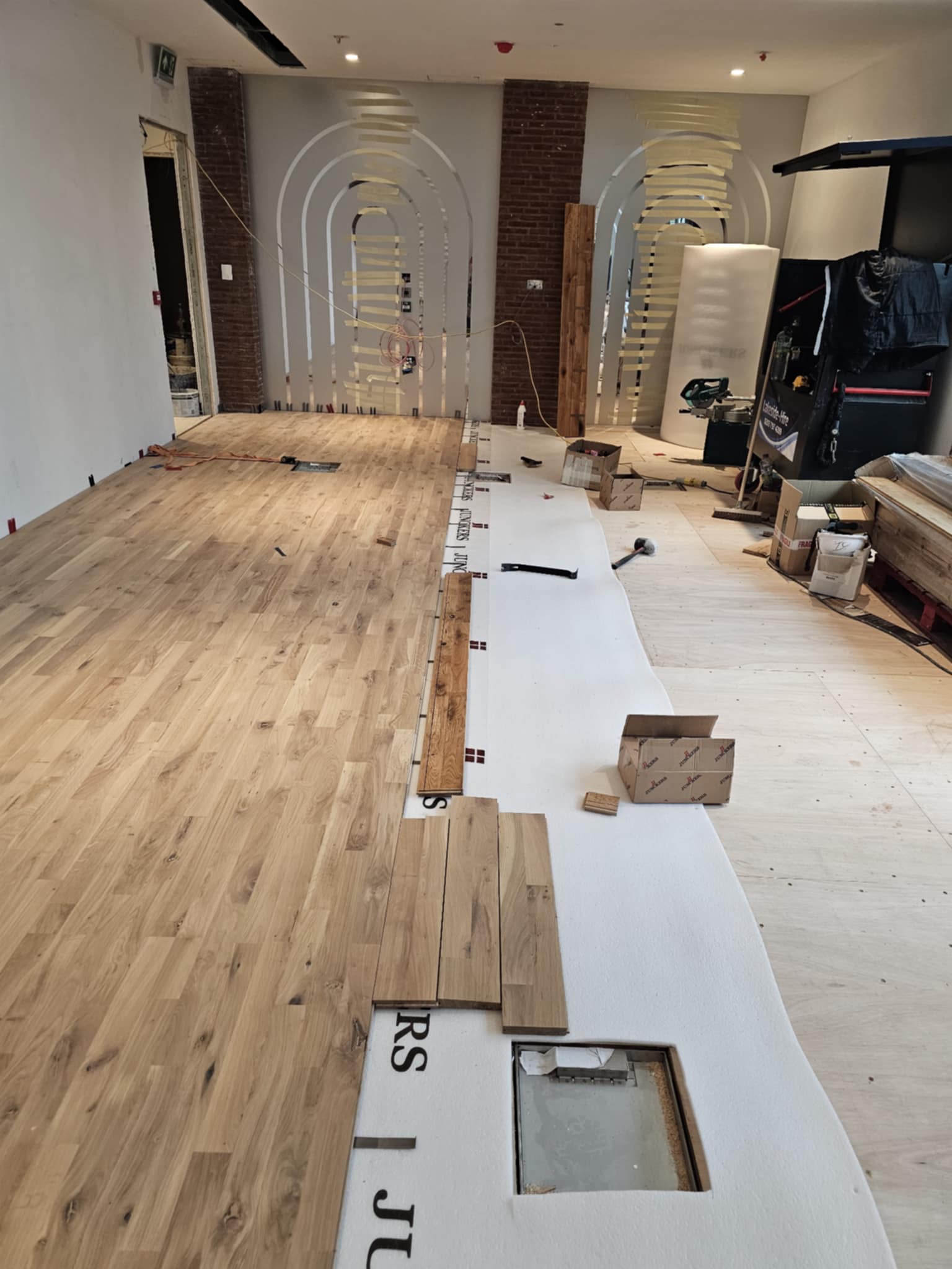 DWELLUX engineered oak flooring installation with arched doorways and brick feature columns