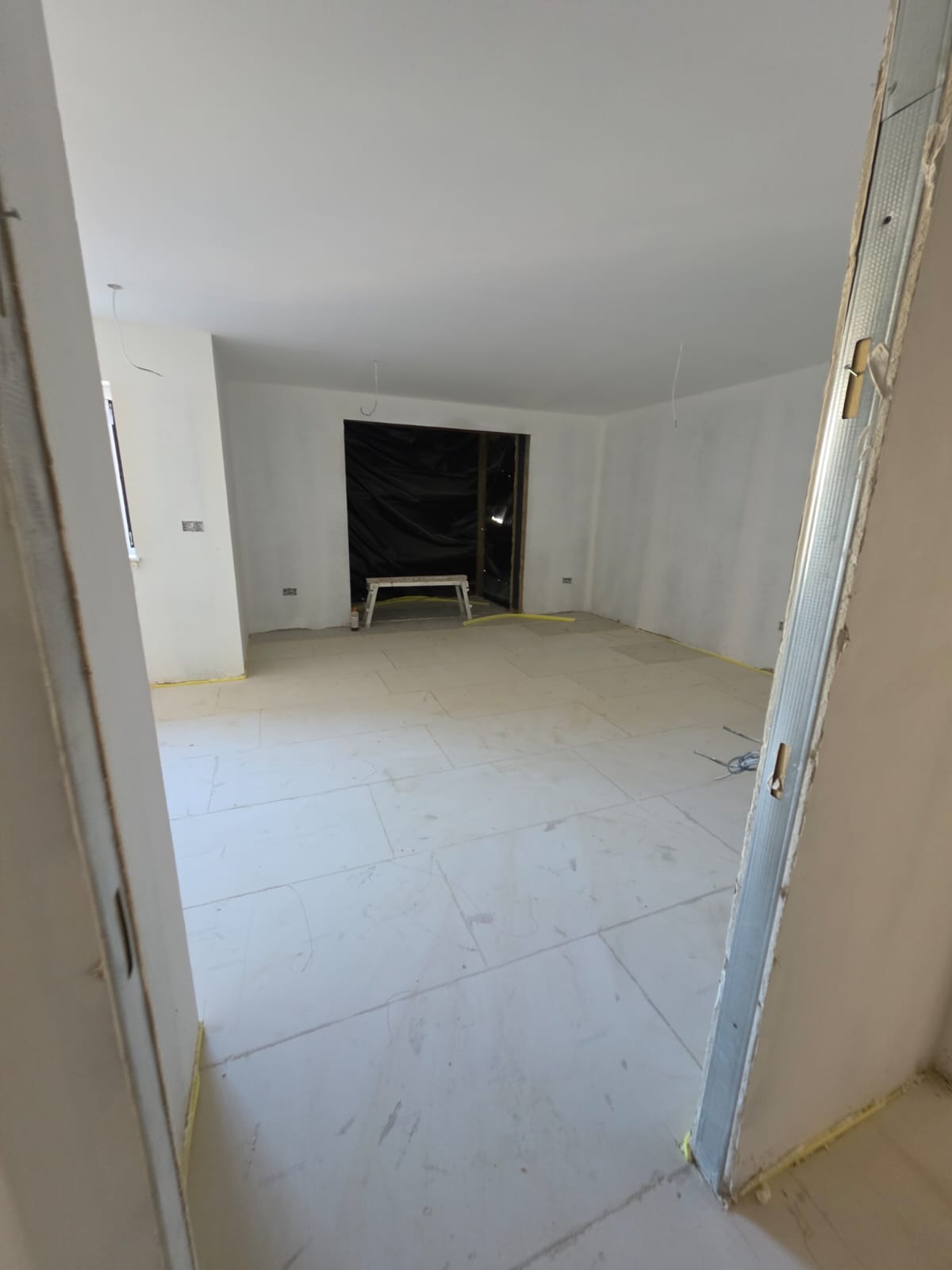 Prepared subfloor panels fully laid and levelled through doorway opening into adjoining reception in Southend-on-Sea