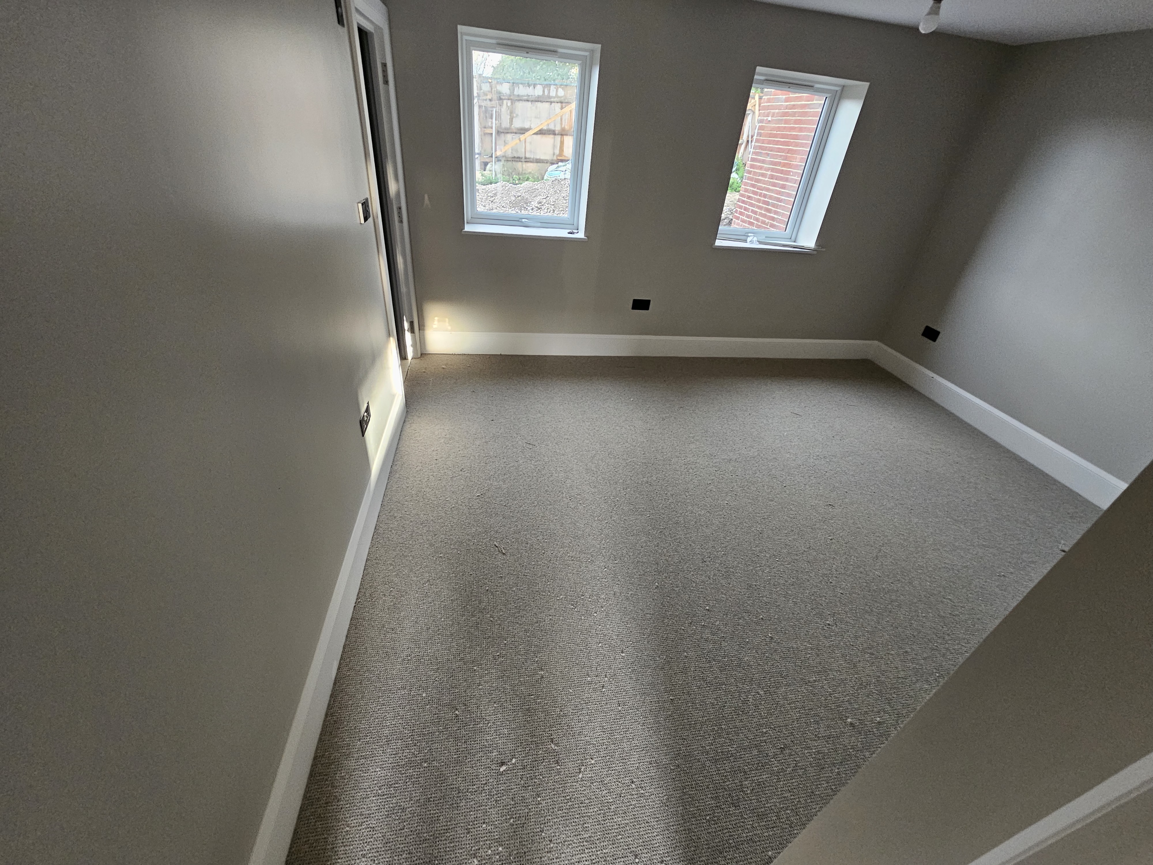 Completed DWELLUX room with new grey carpet flooring, white skirting boards and freshly painted walls