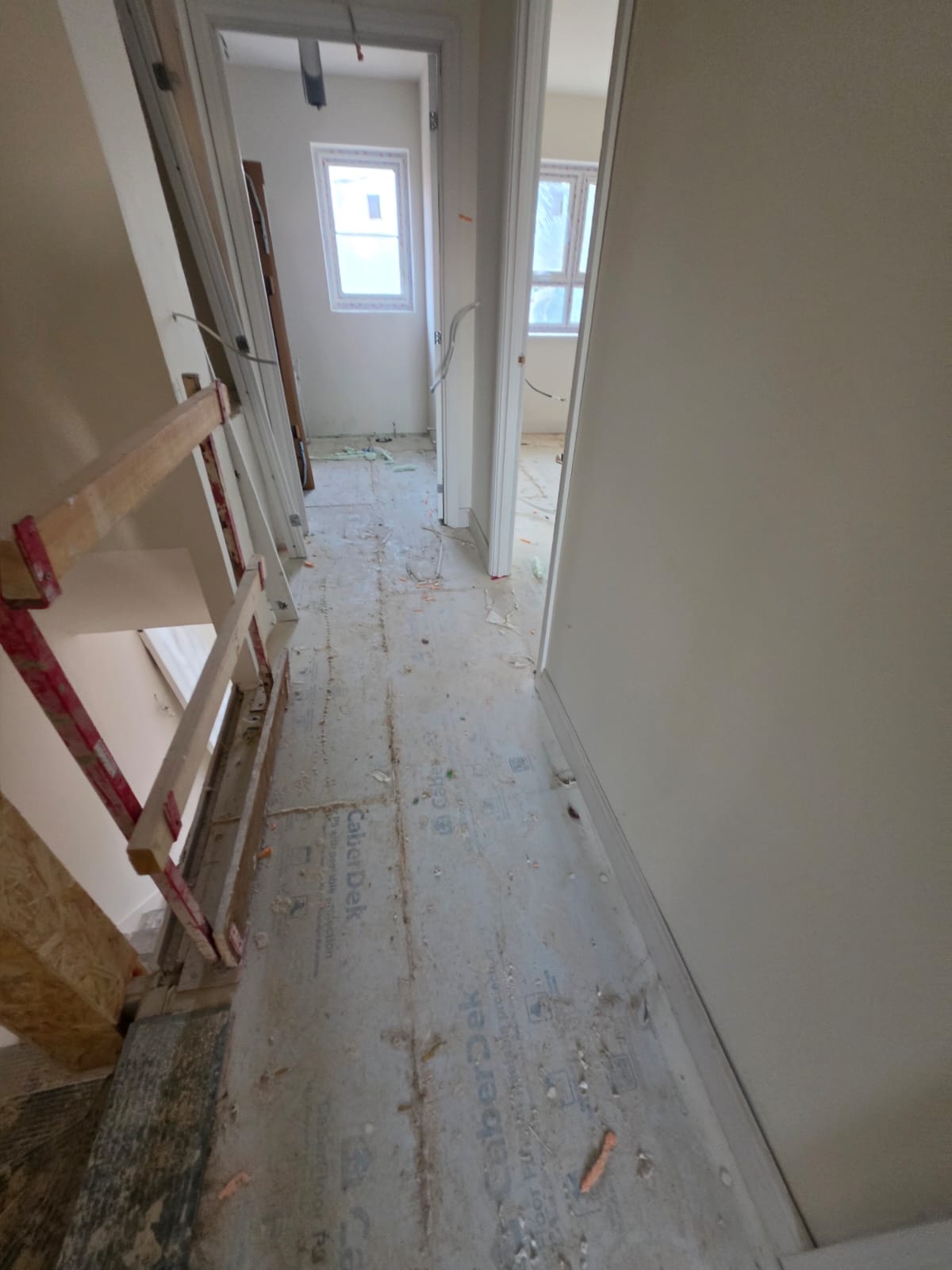 First floor landing carpentry corridor with CaberDek subfloor protection and door frames in Harlow by DWELLUX