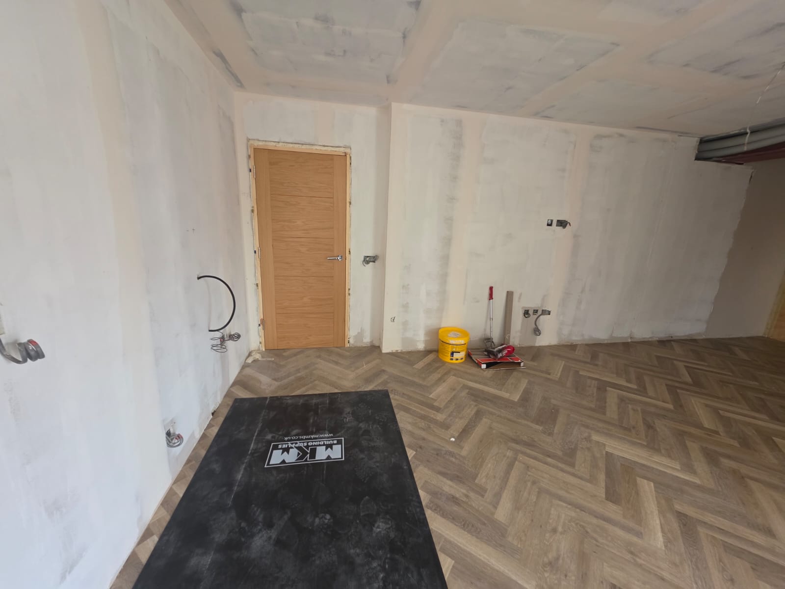 Herringbone parquet flooring installation completed with oak internal door and temporary floor protection in Southend-on-Sea by DWELLUX