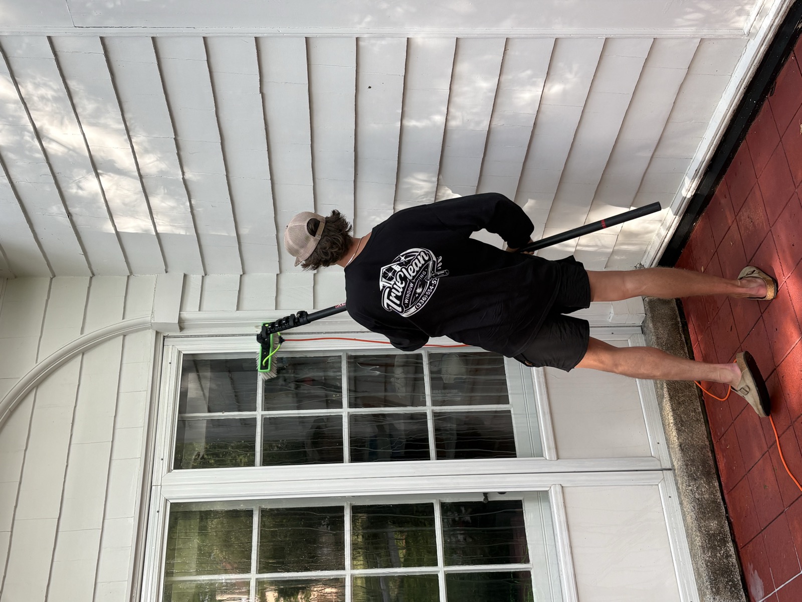TrueClean crew washing a house exterior from the ground with a pole, no ladders