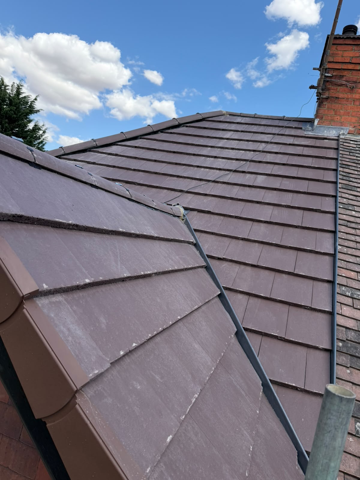 Completed brown interlocking tiled roof with dry ridge, valleys and lead flashing