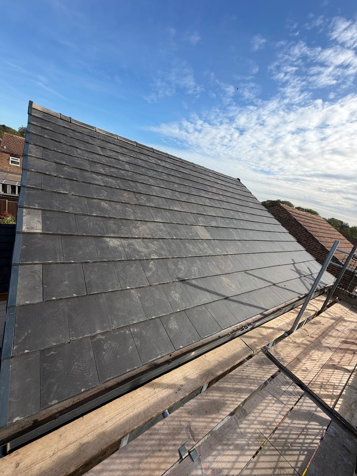 New slate tile pitched roof installation with dry verge system and scaffolding