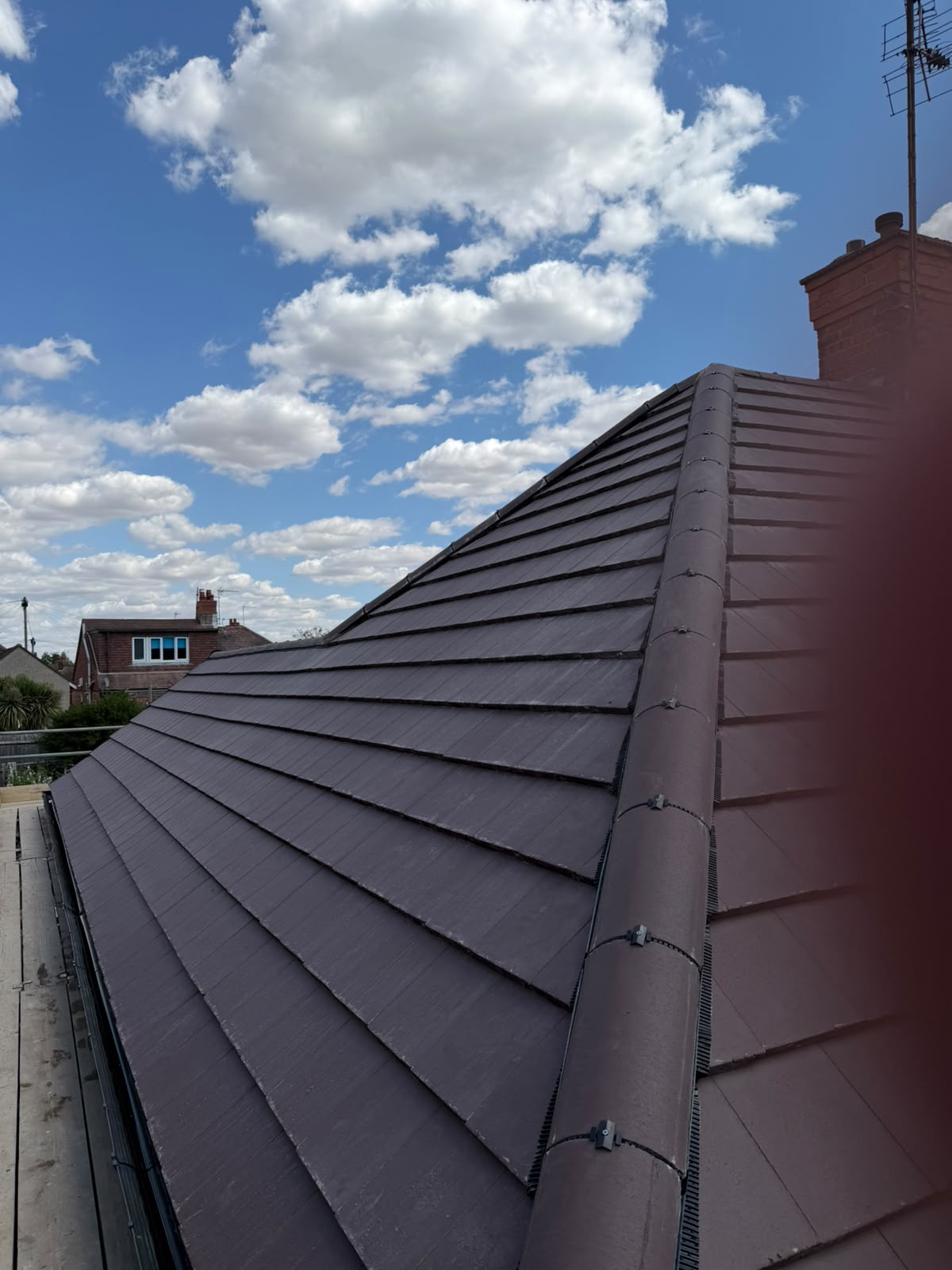 Completed dark grey tiled roof installation with dry ridge and hip system