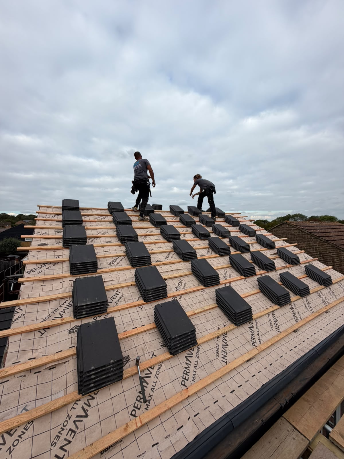 Evenly distributed tile stacks across roof battens ready for fixing