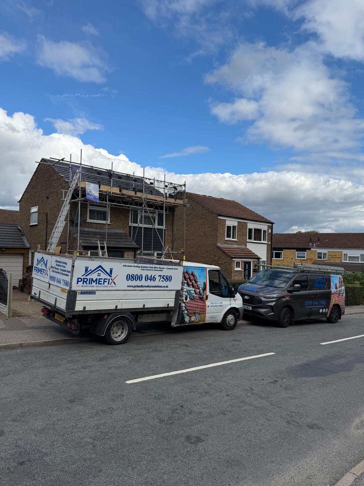 Primefix vehicles and scaffolding set up for roof repair on residential property