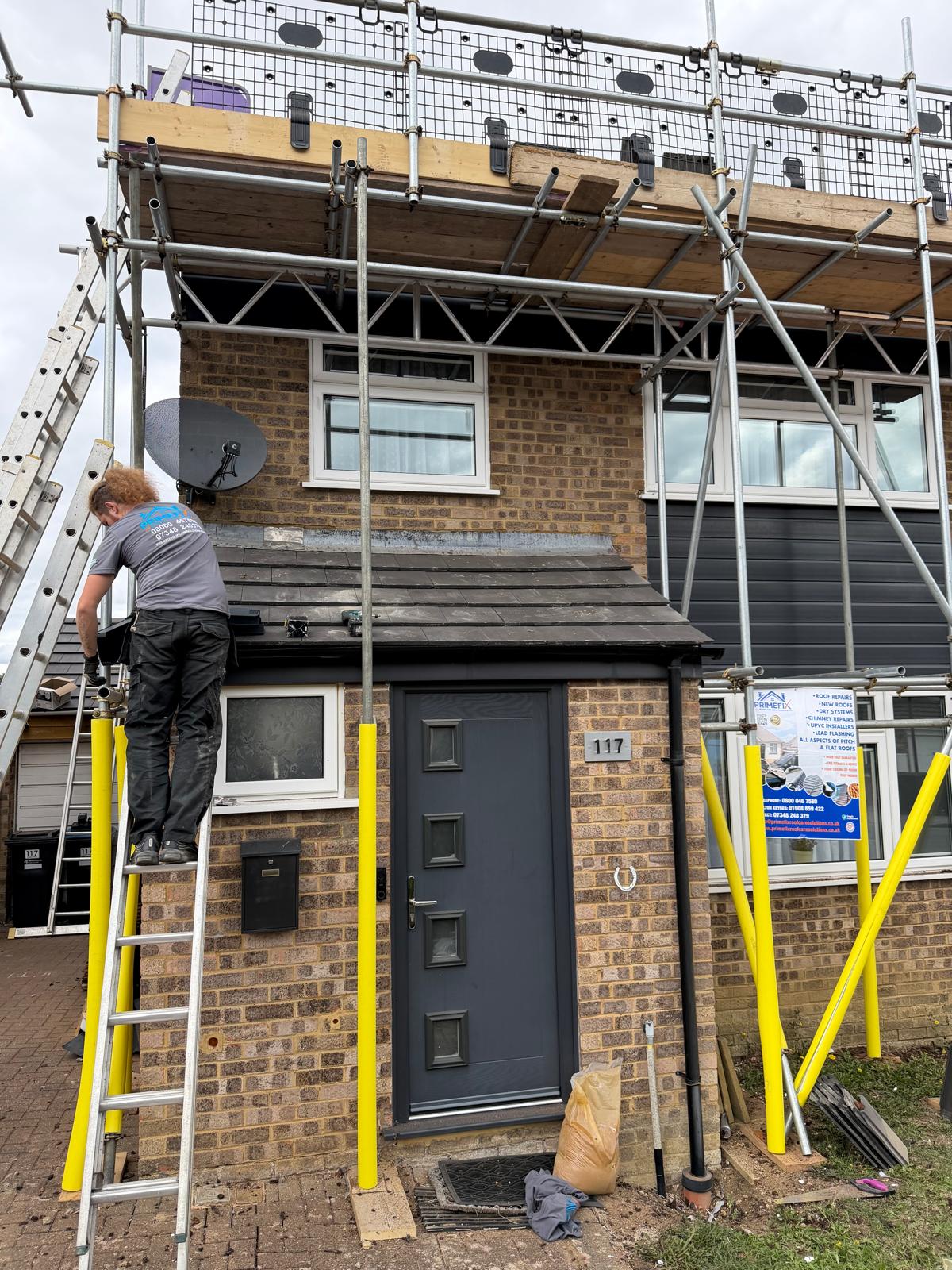 Primefix roofer fitting porch roof tiles and roofline details on ladder