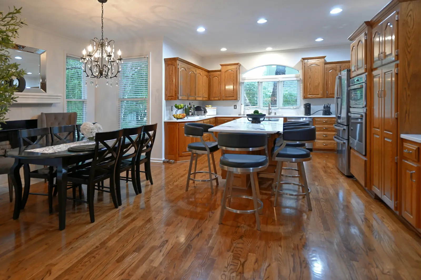 Kitchen remodel in Overland Park, Kansas, featuring natural wood cabinetry, a center island with seating, stainless steel appliances, and hardwood flooring.
