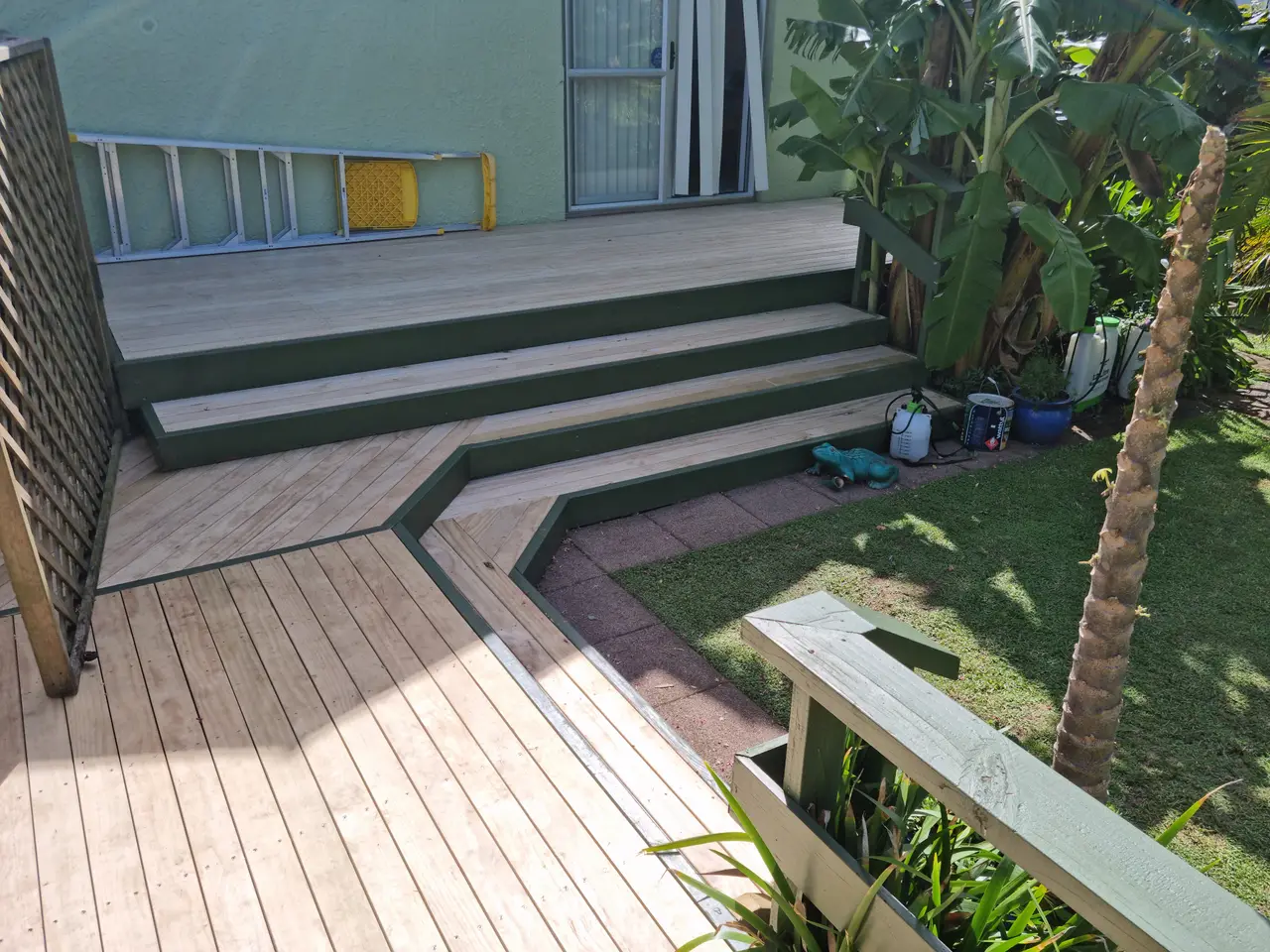 Multi-Level Deck with Wrap-Around Steps - The completed multi-level deck with wrap-around steps, clean timber decking and painted green trim leading out to the garden.