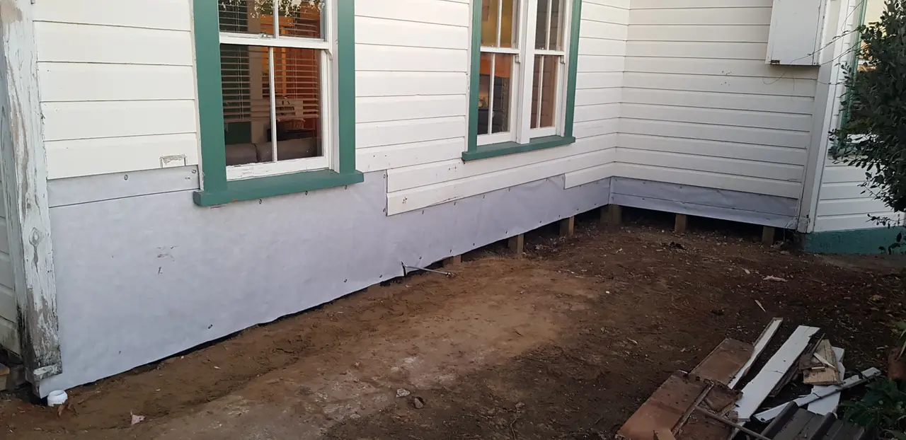 General Maintenance - Corner of the house mid-repair, with framing exposed and new cladding being prepared.