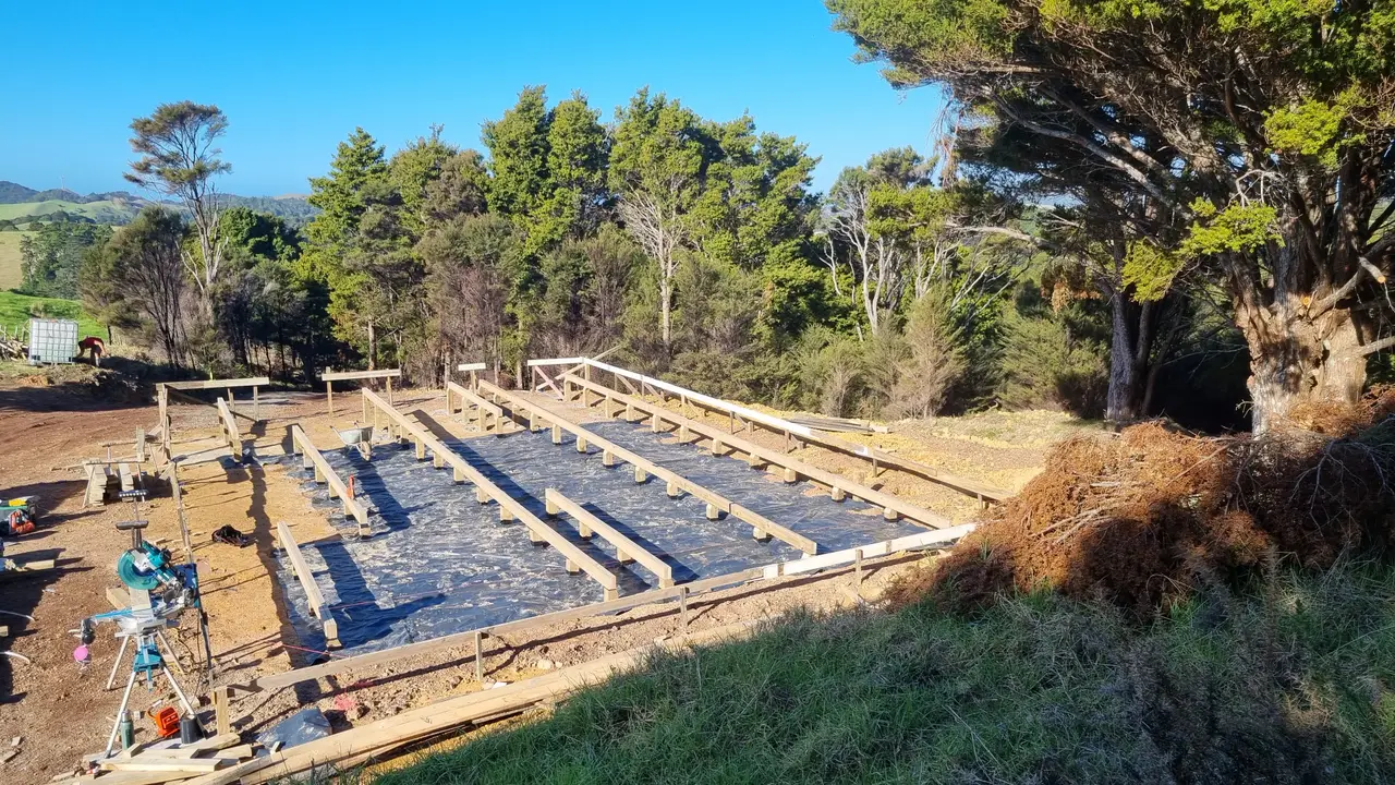 Residential Extension & Subfloor Framing Build - Polythene moisture barrier laid and timber bearers aligned, with heavy subfloor bearers set across the piles.