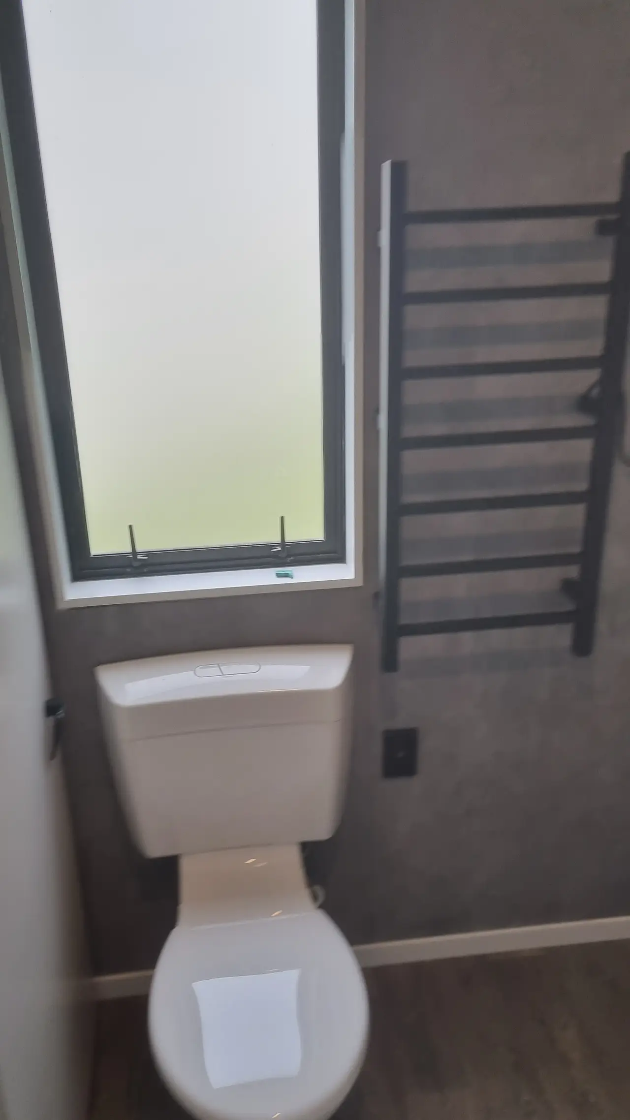 Modern Ensuite Renovation - Dual-flush toilet installed beneath the window with wall-mounted black heated towel rail.