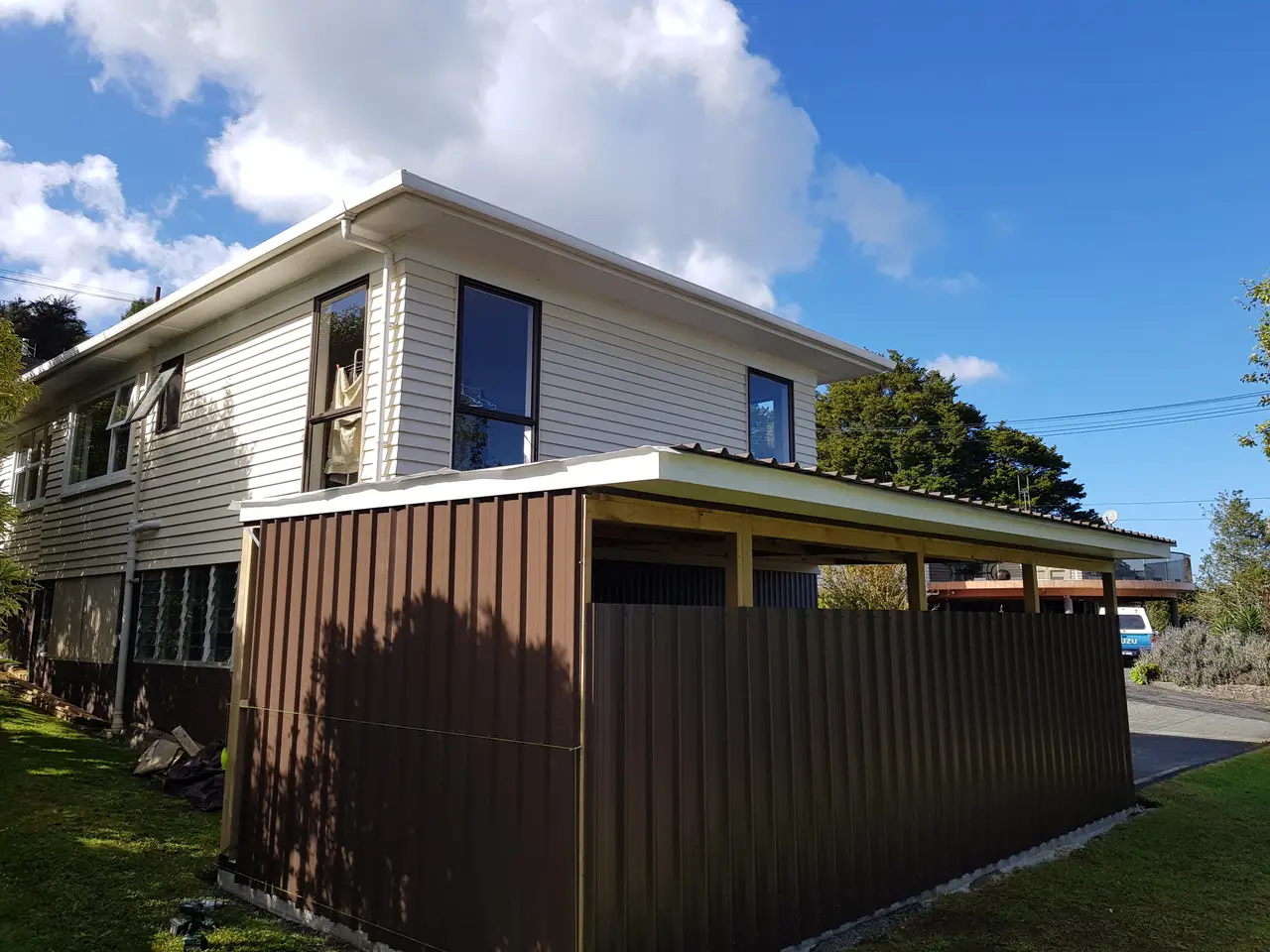 Attached Covered Carport & Storage Enclosure Addition - Completed attached covered carport and utility enclosure addition, with solid timber framing, custom metal roofing and cladding built against the two-storey home.