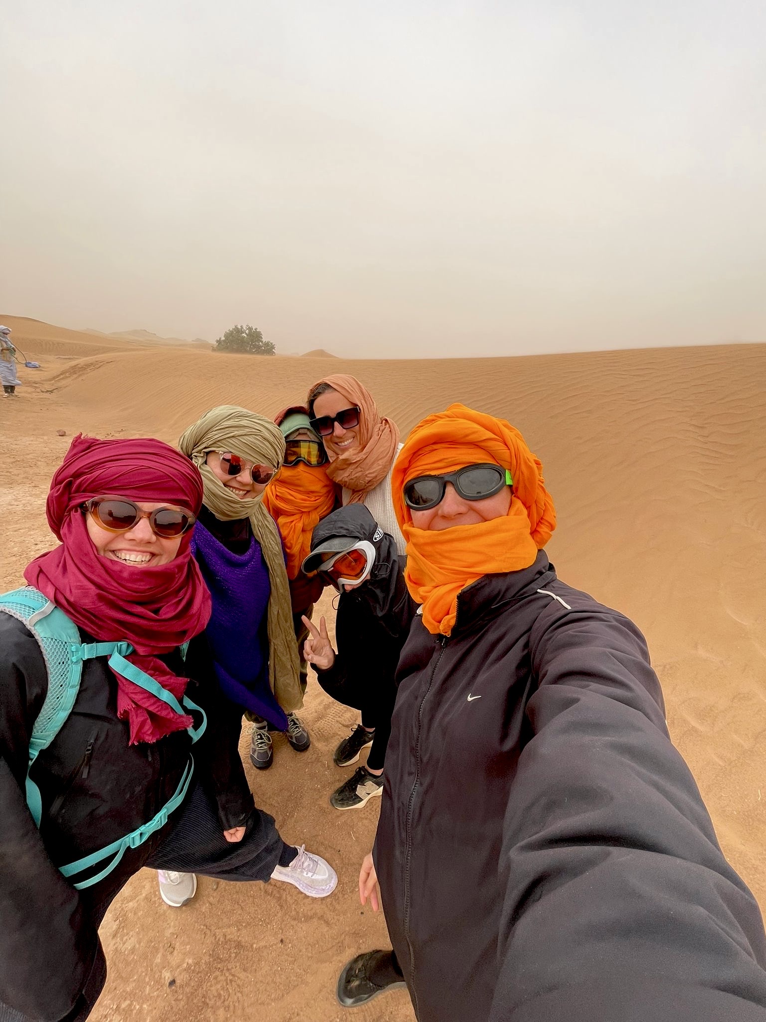 Women with turbans standing together on the desert dunes