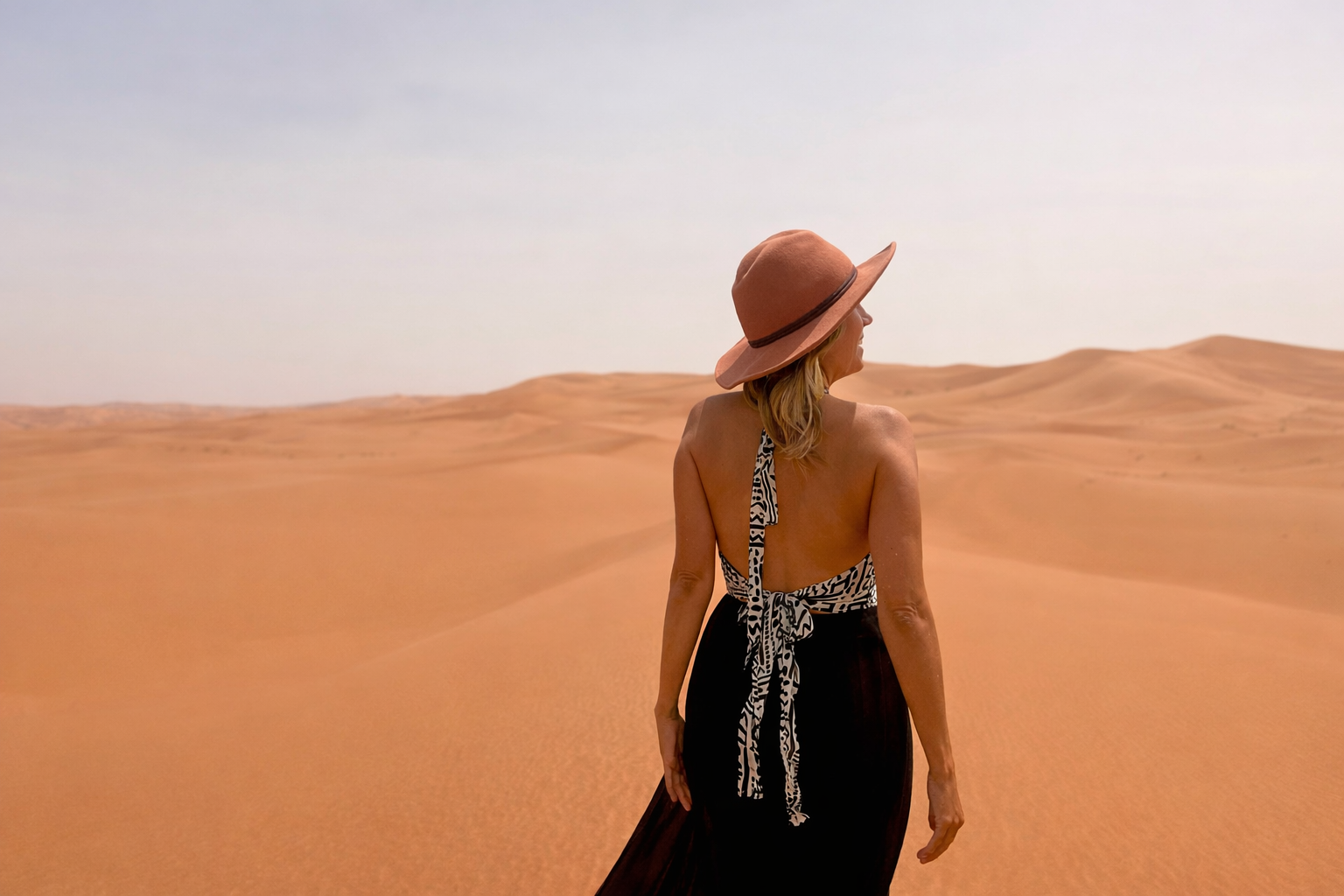 Woman looking out over expansive Sahara sand dunes