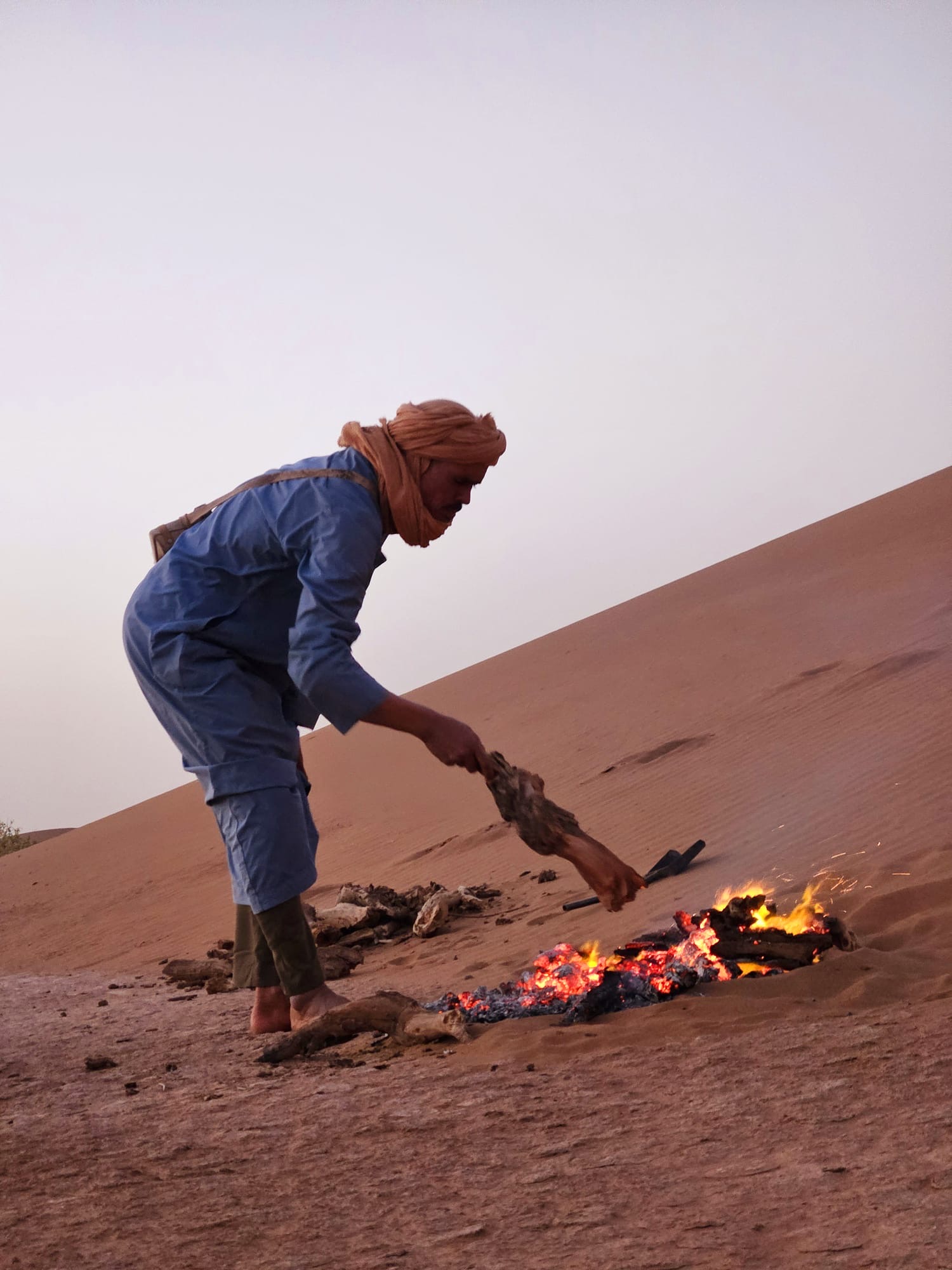 Nomad tending fire on the Sahara sand dune