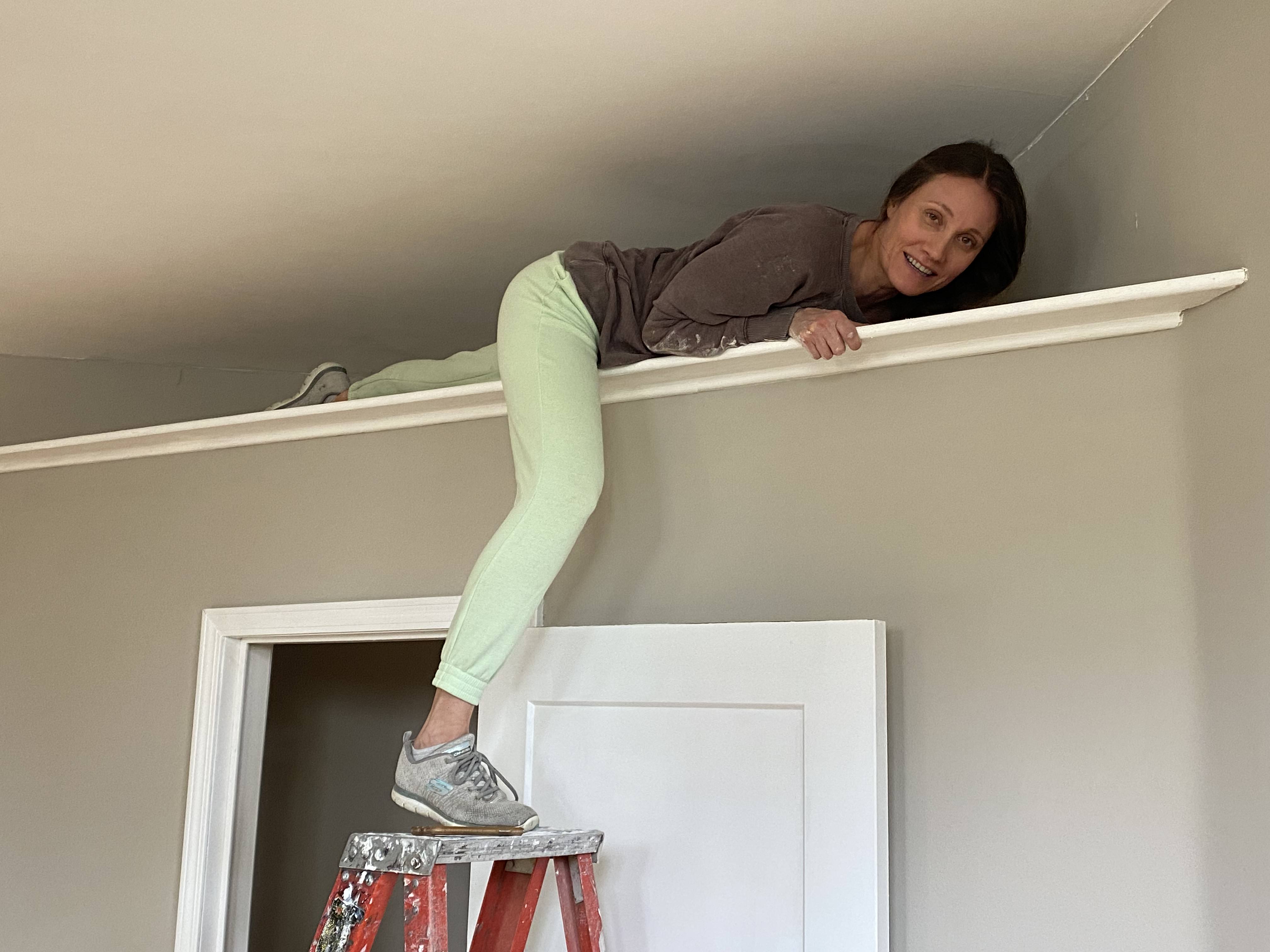 Dawn Herrema installing crown molding during a home renovation