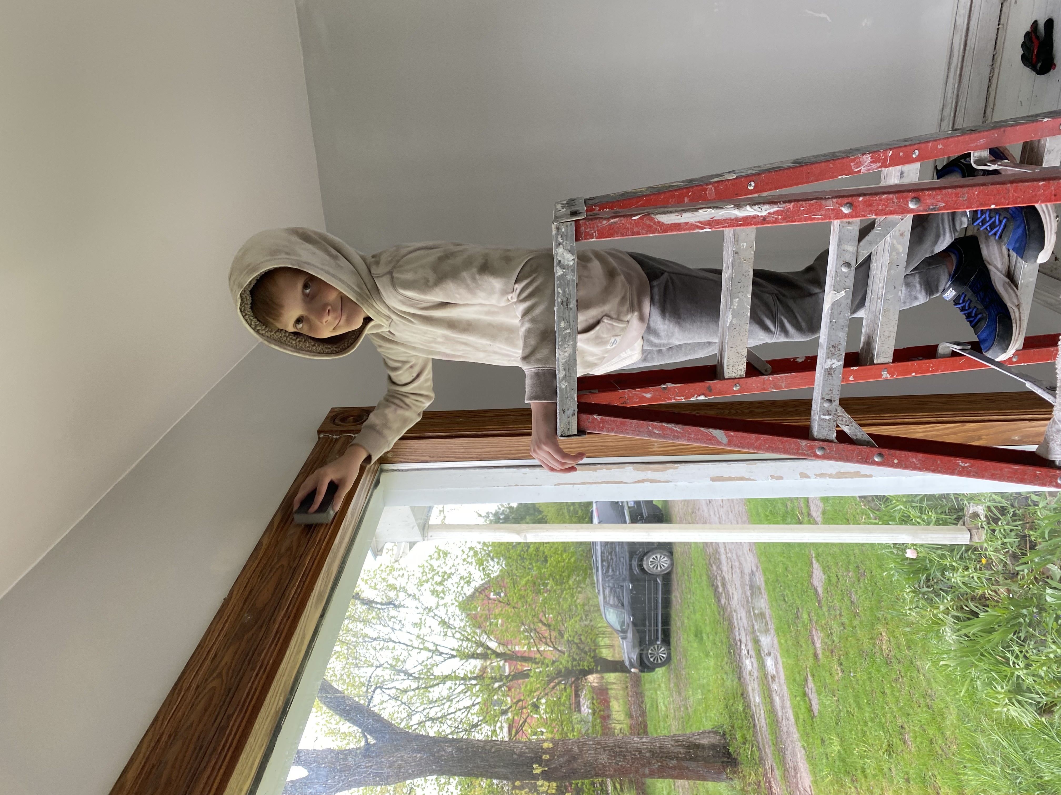 One of Justin's sons helping sand window trim during a renovation