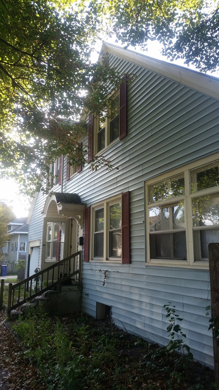 Exterior — Faded Siding & Overgrown Yard — before