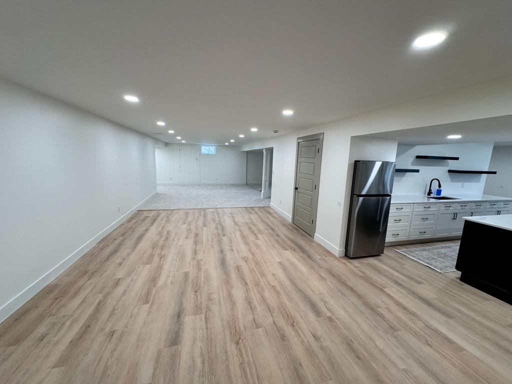 Open-concept finished basement with wet bar kitchenette and luxury vinyl flooring
