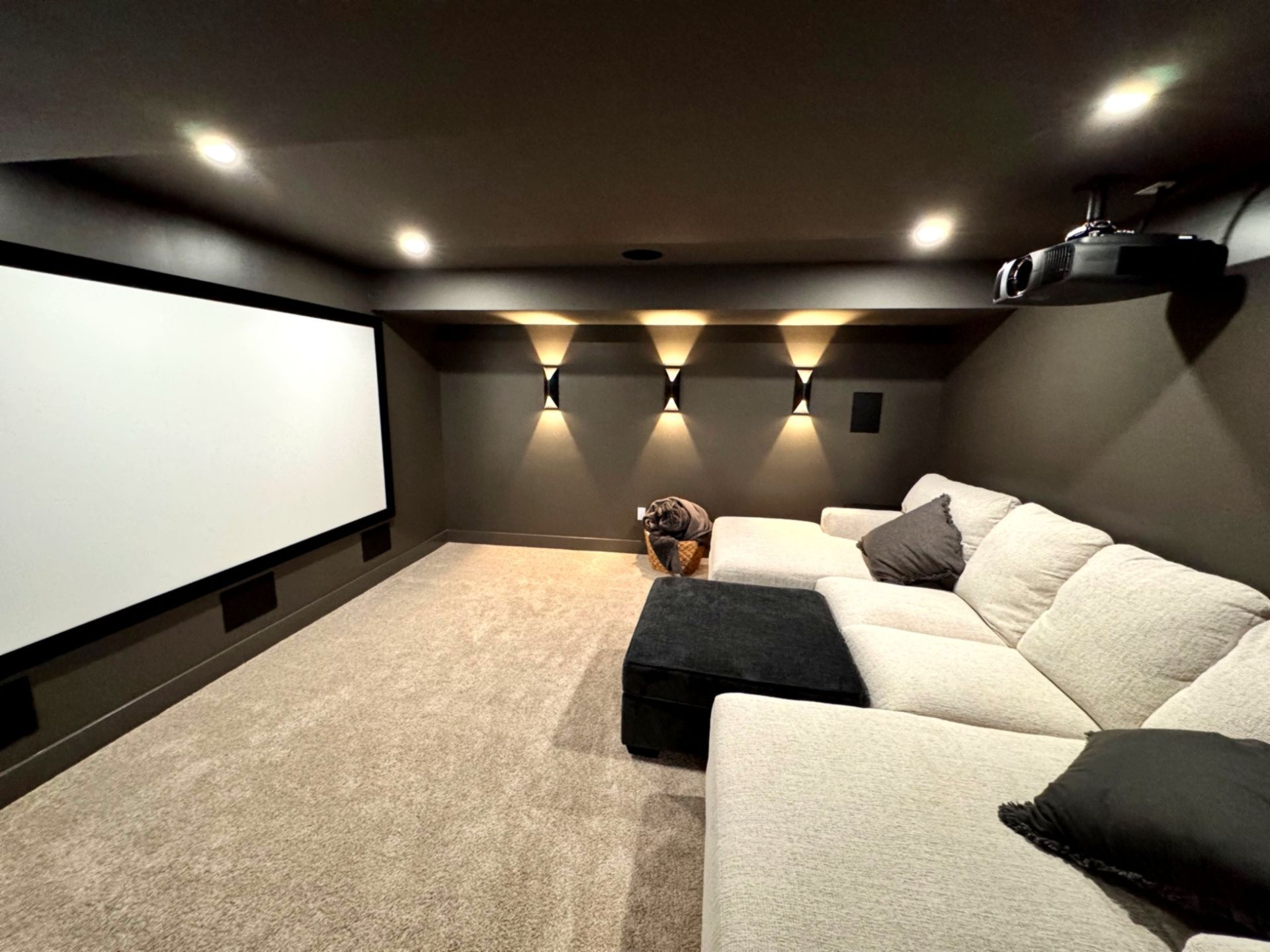 Luxury home theater and entertainment basement with projector and plush sectional