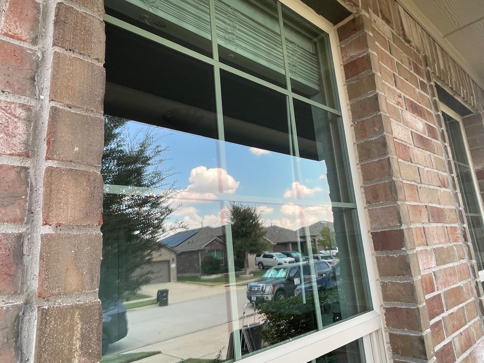 Residential brick home window crystal clear with crisp reflection after professional cleaning