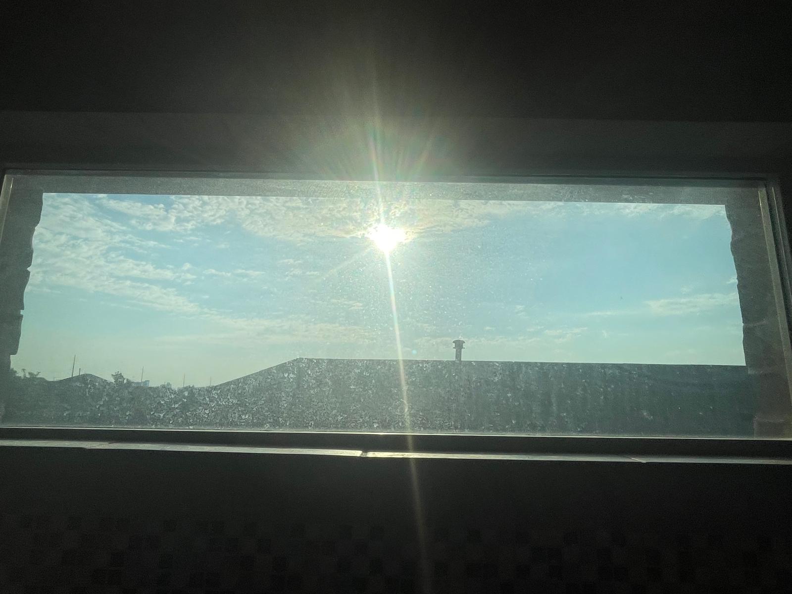Interior view of clerestory window with mineral haze, dust, and sun glare before professional cleaning