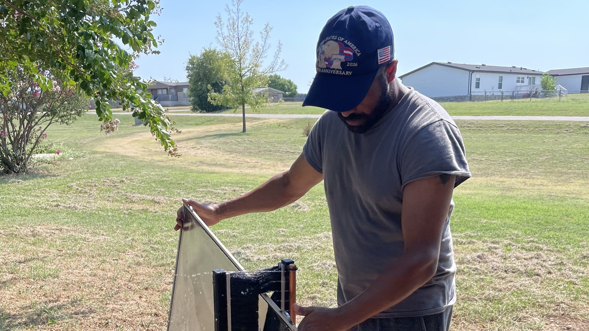 Abraham washing a window screen with pure-water spray on a North Texas lawn