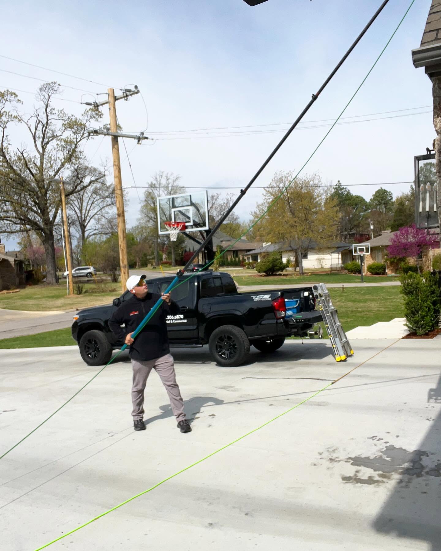 Team member using water-fed pole on residential driveway