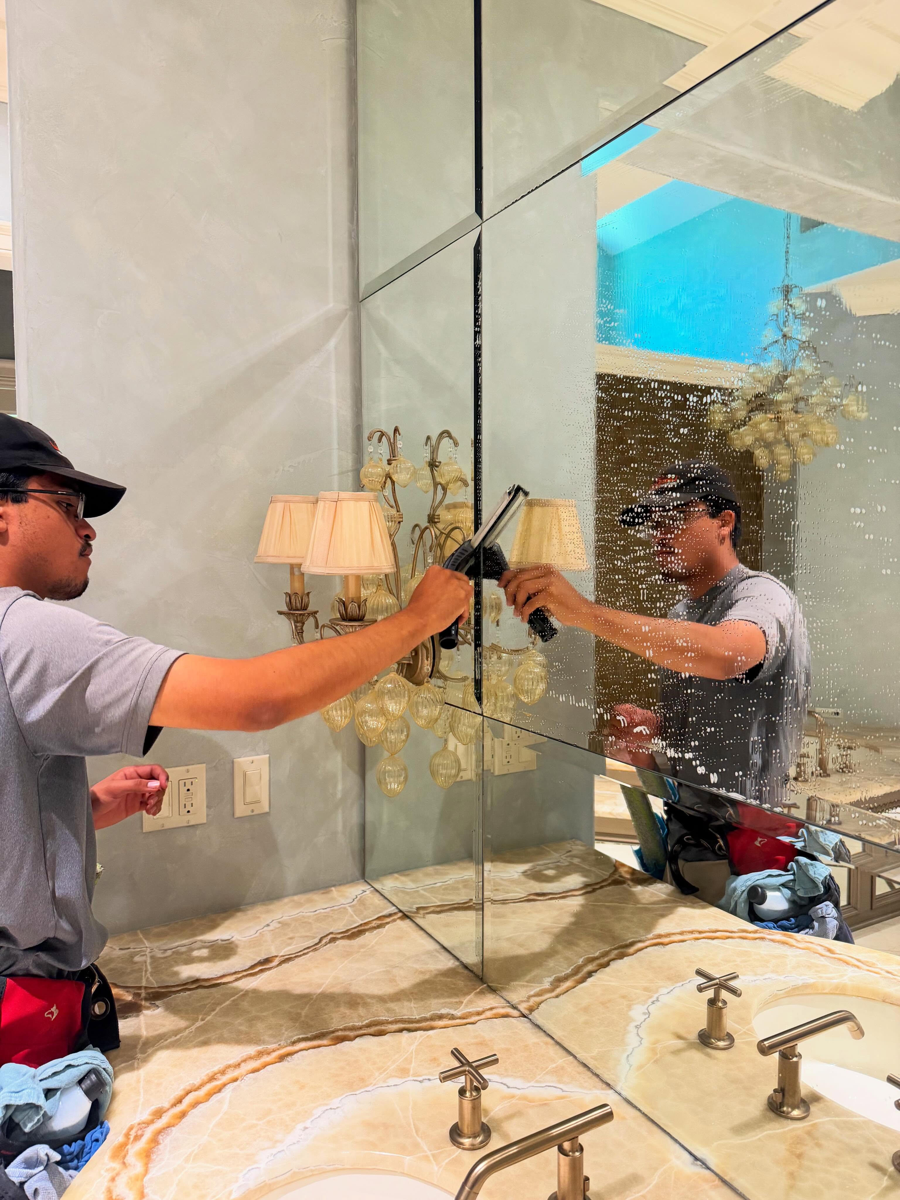 Technician cleaning interior glass mirrors in luxury bathroom
