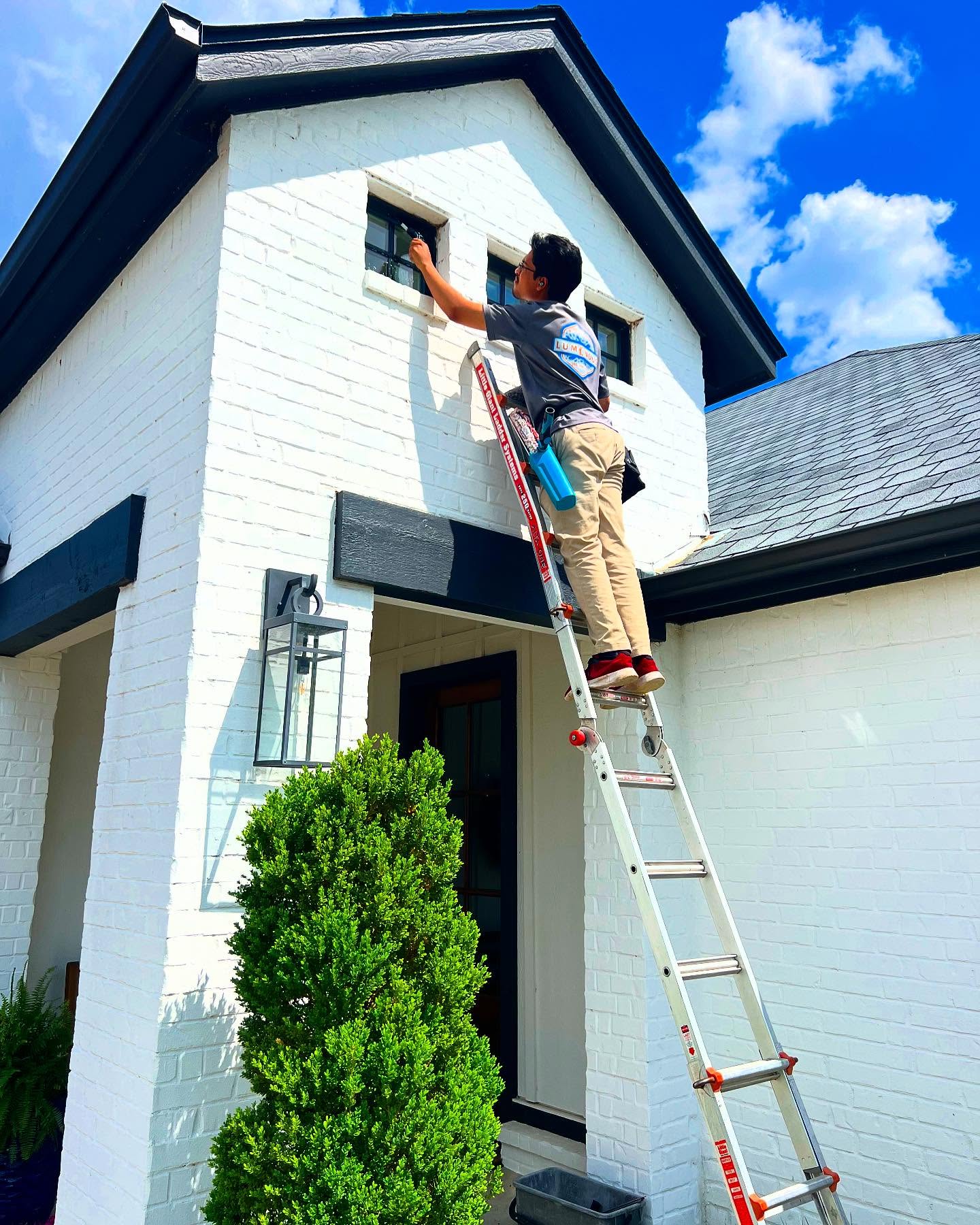 Luminous technician on ladder cleaning upper windows