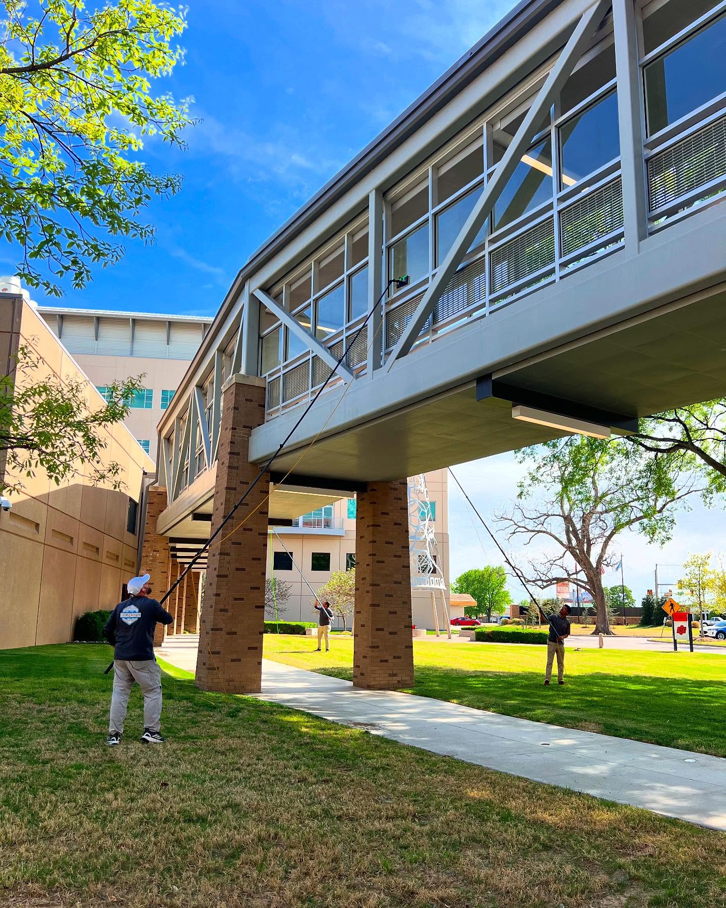 Technician cleaning skybridge windows with pole system