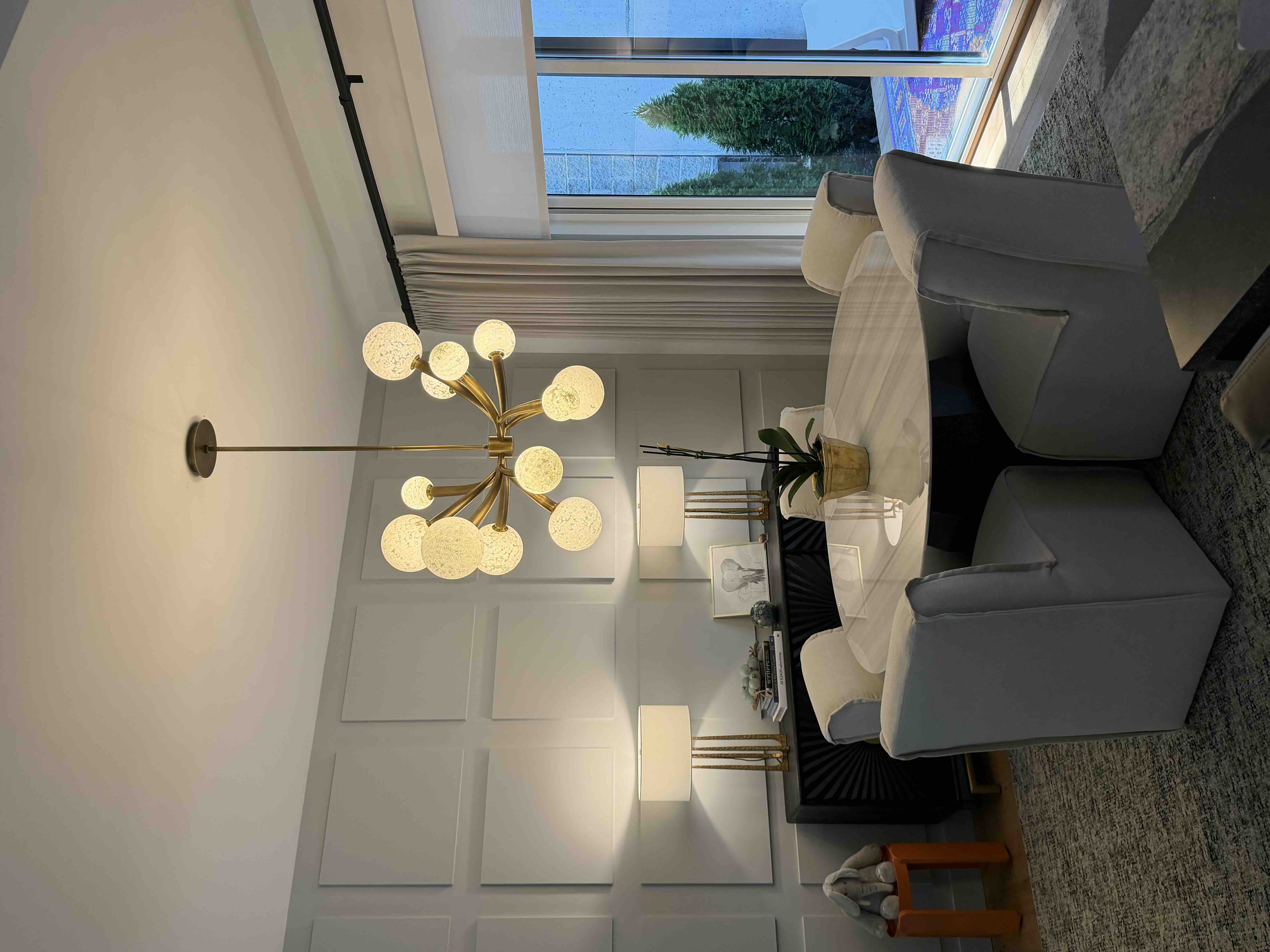 Brass sputnik-style chandelier with round textured glass globes installed above a living room seating area