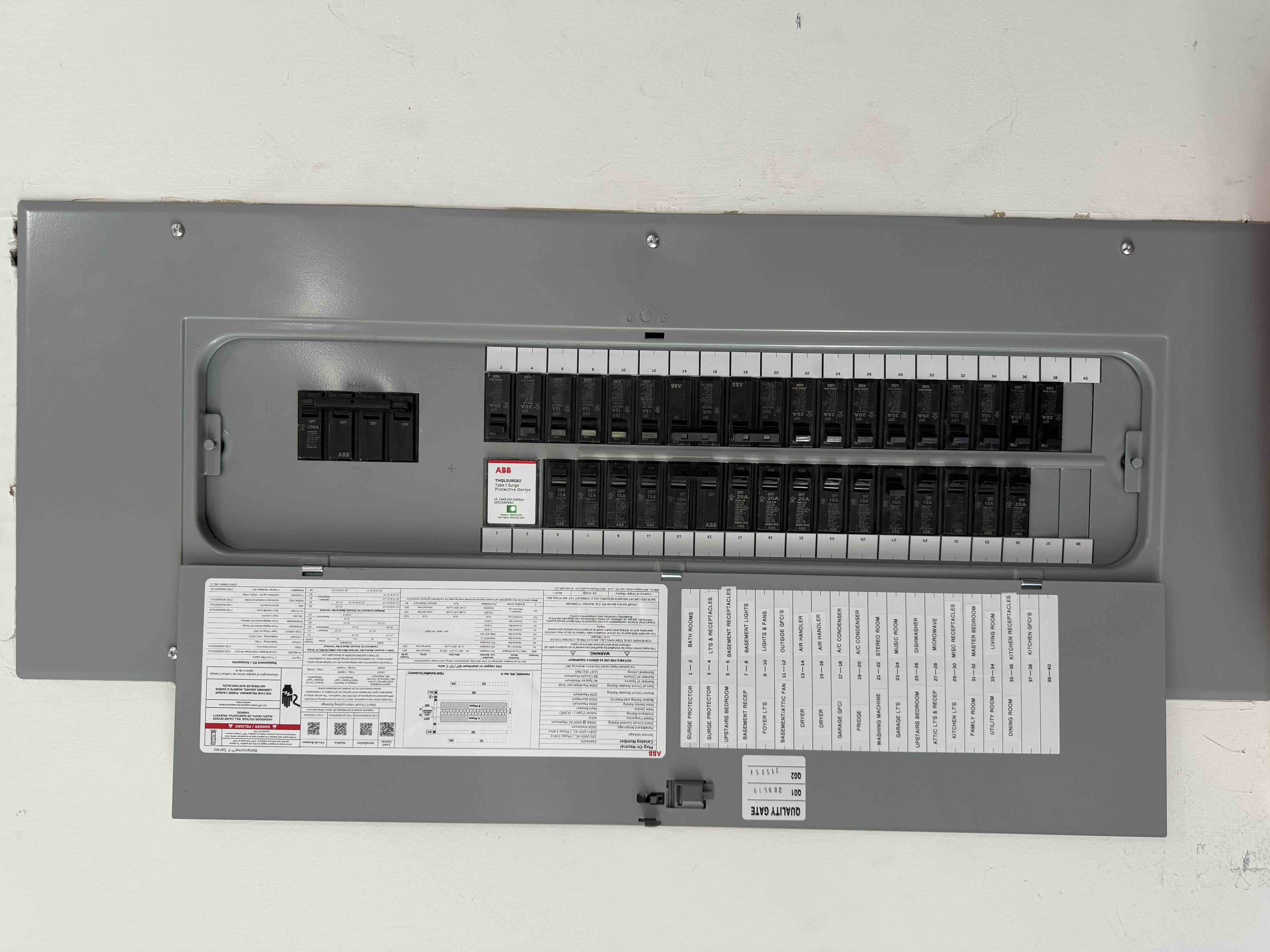 Completed ABB breaker panel with the door closed, showing a printed circuit directory card labeling every room and circuit