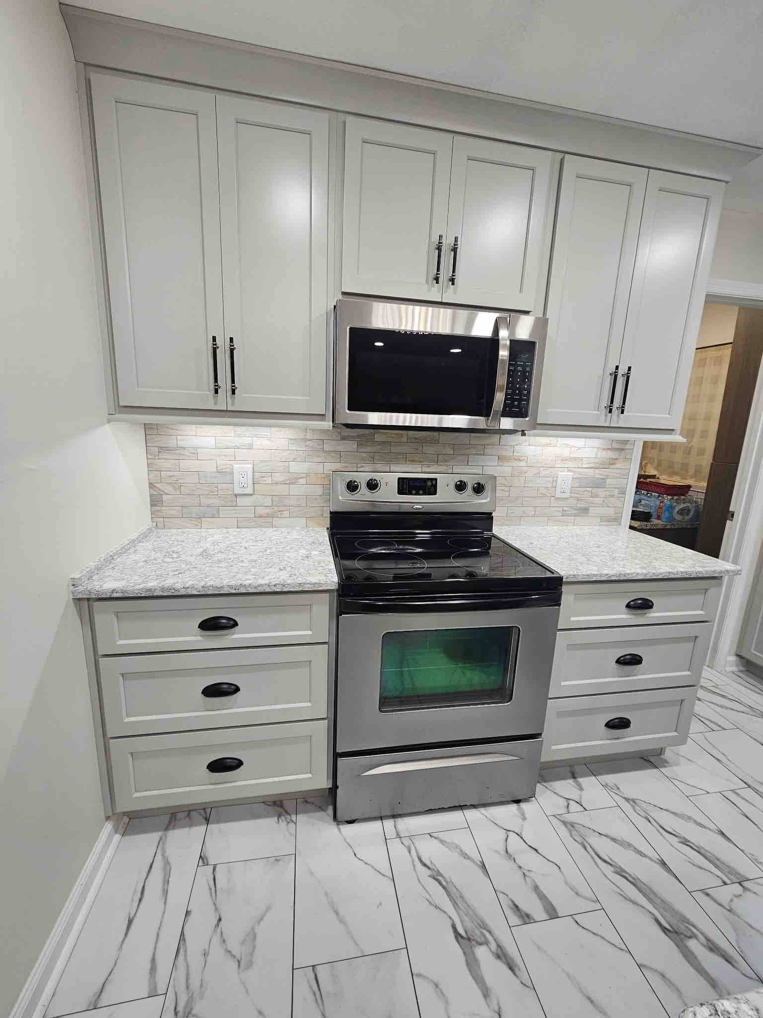 Electric range and over-the-range microwave with properly placed outlets in a renovated kitchen backsplash