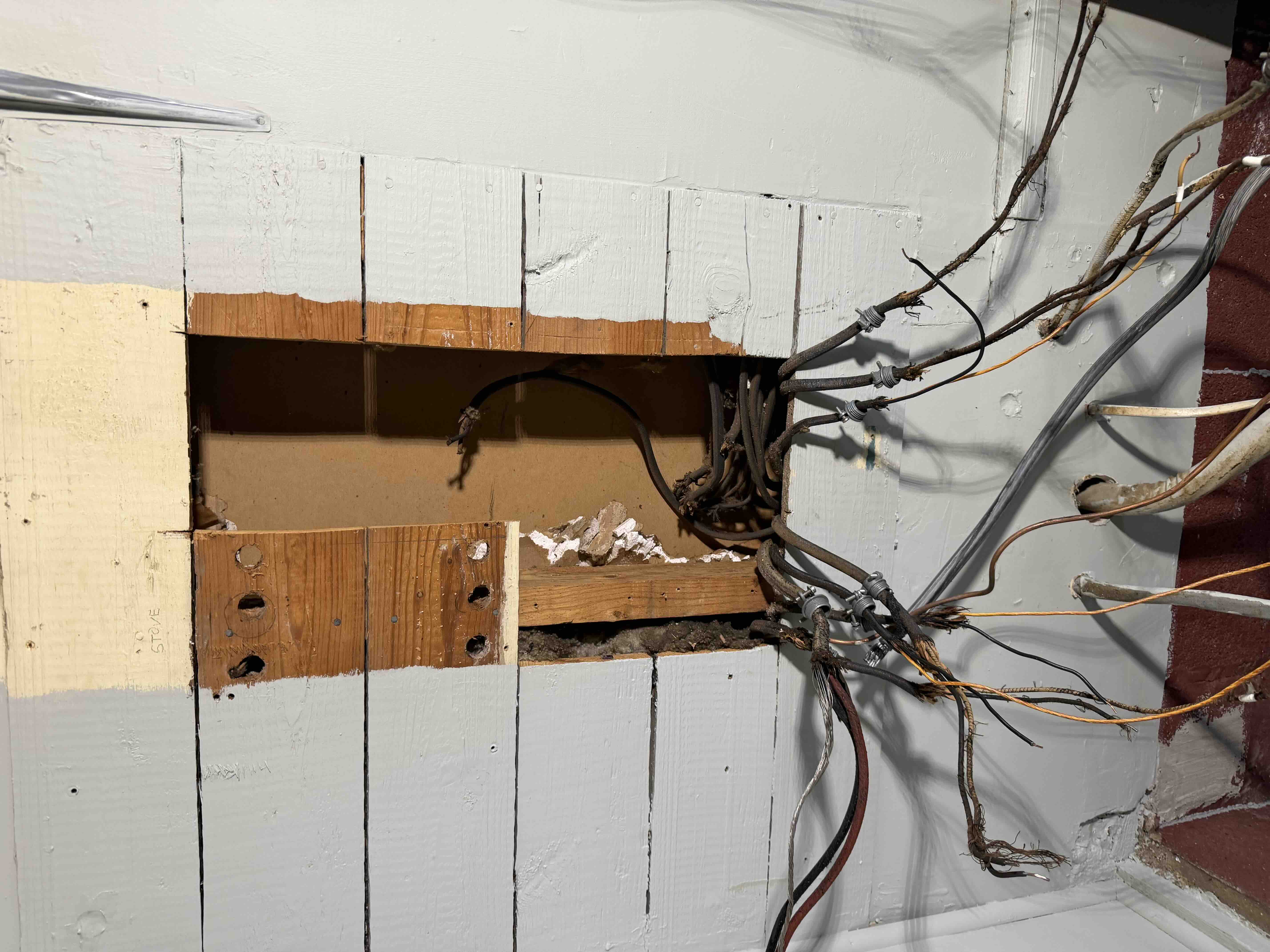 Wall opening with old panel removed and branch circuit wiring prepped for a new breaker panel installation
