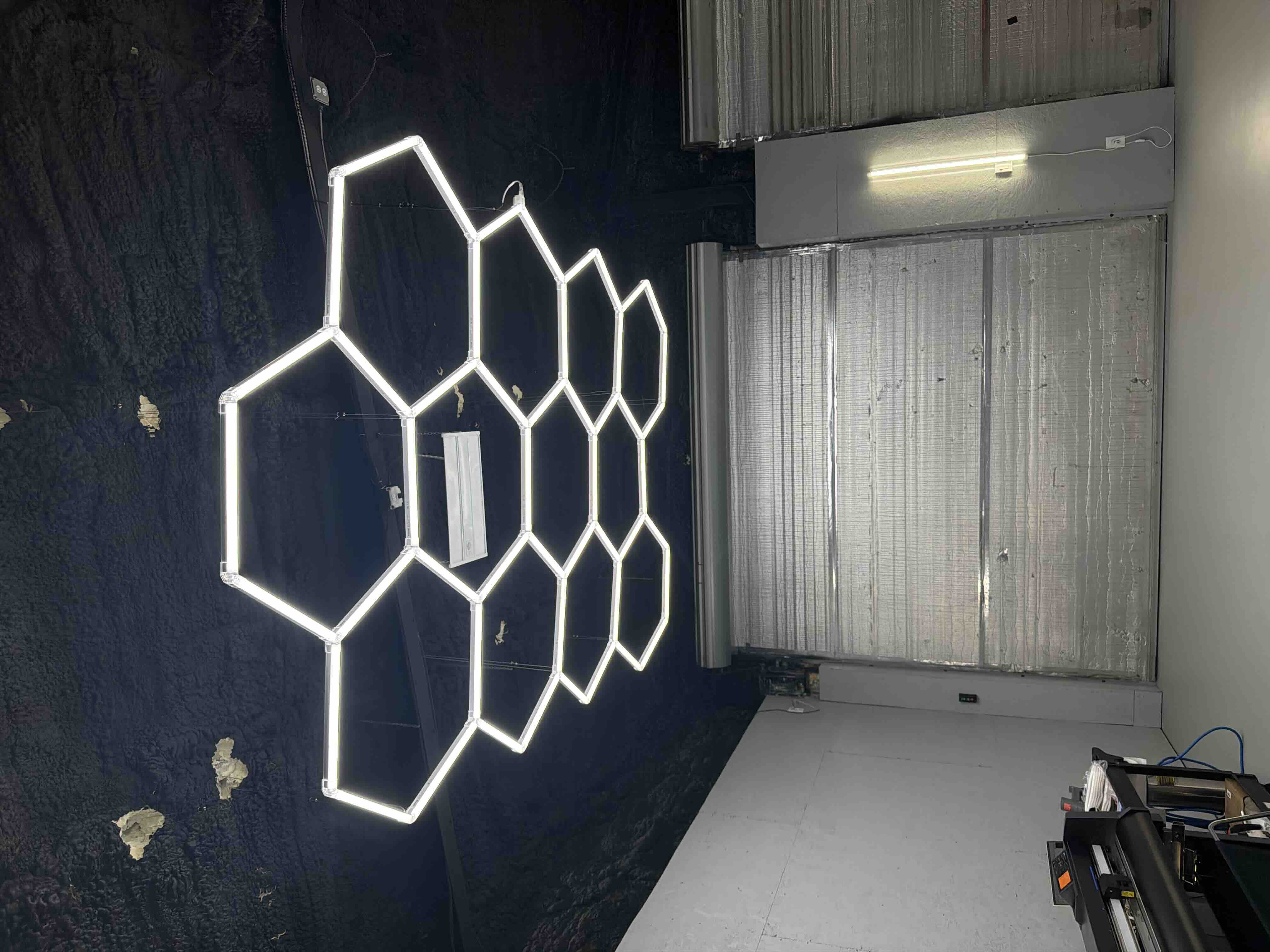 Hexagon-shaped LED light panels arranged in a honeycomb pattern, illuminated during a custom lighting fixture installation