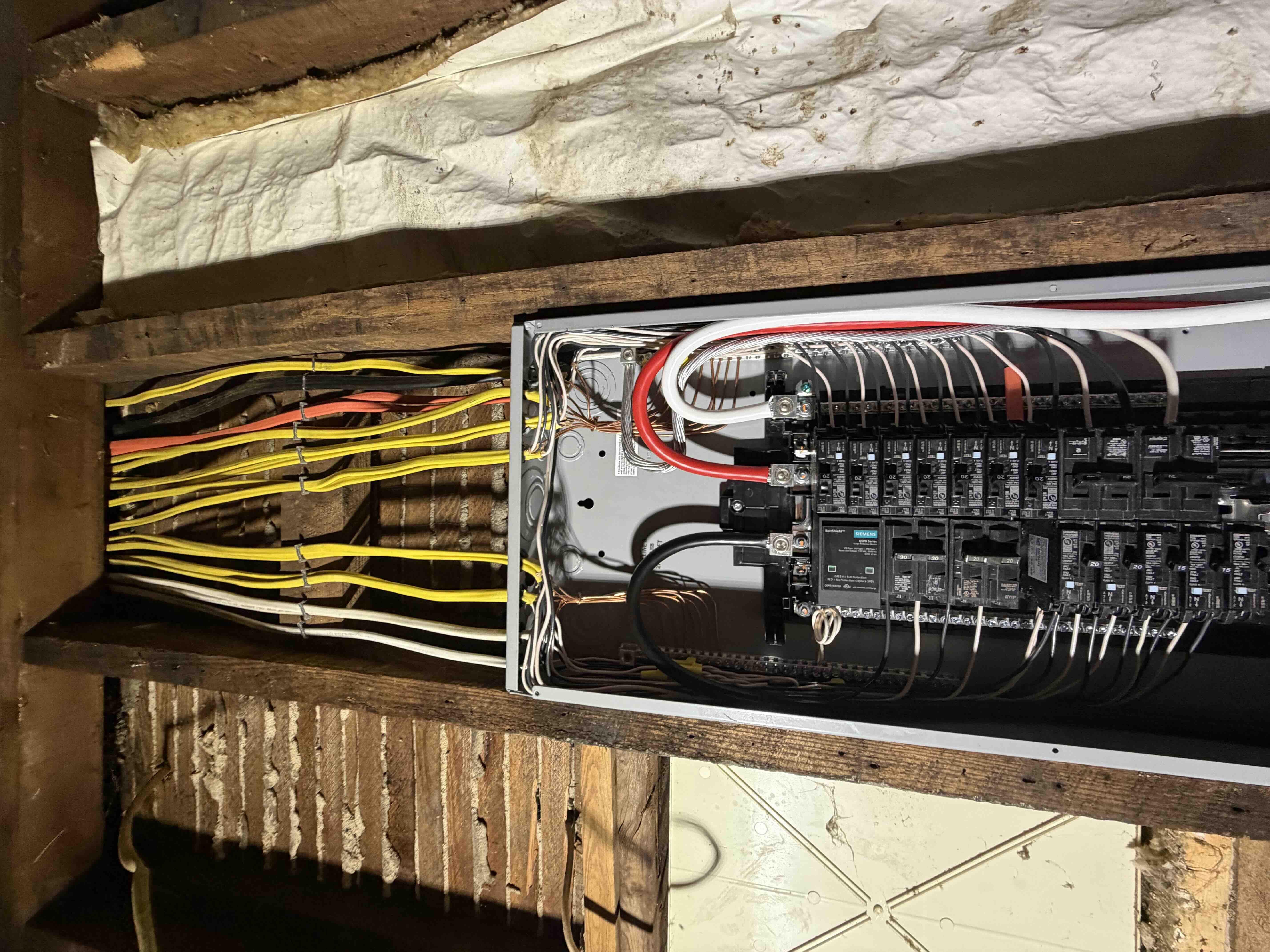 Close view of Romex cables routed neatly into a Siemens load center panel with ground and neutral conductors bonded