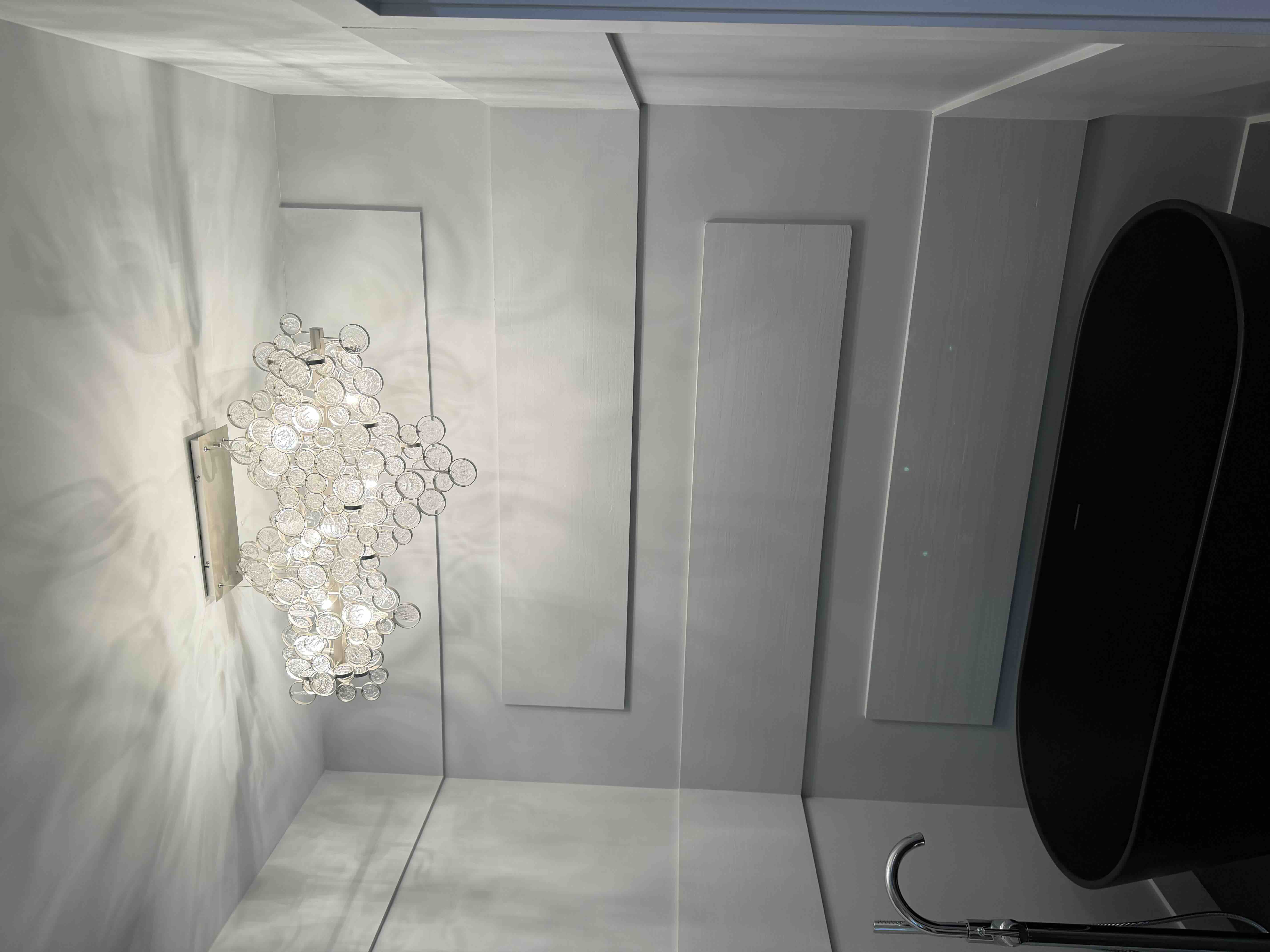 Cluster of round crystal glass orbs forming a wall sconce light fixture, illuminated in an entryway