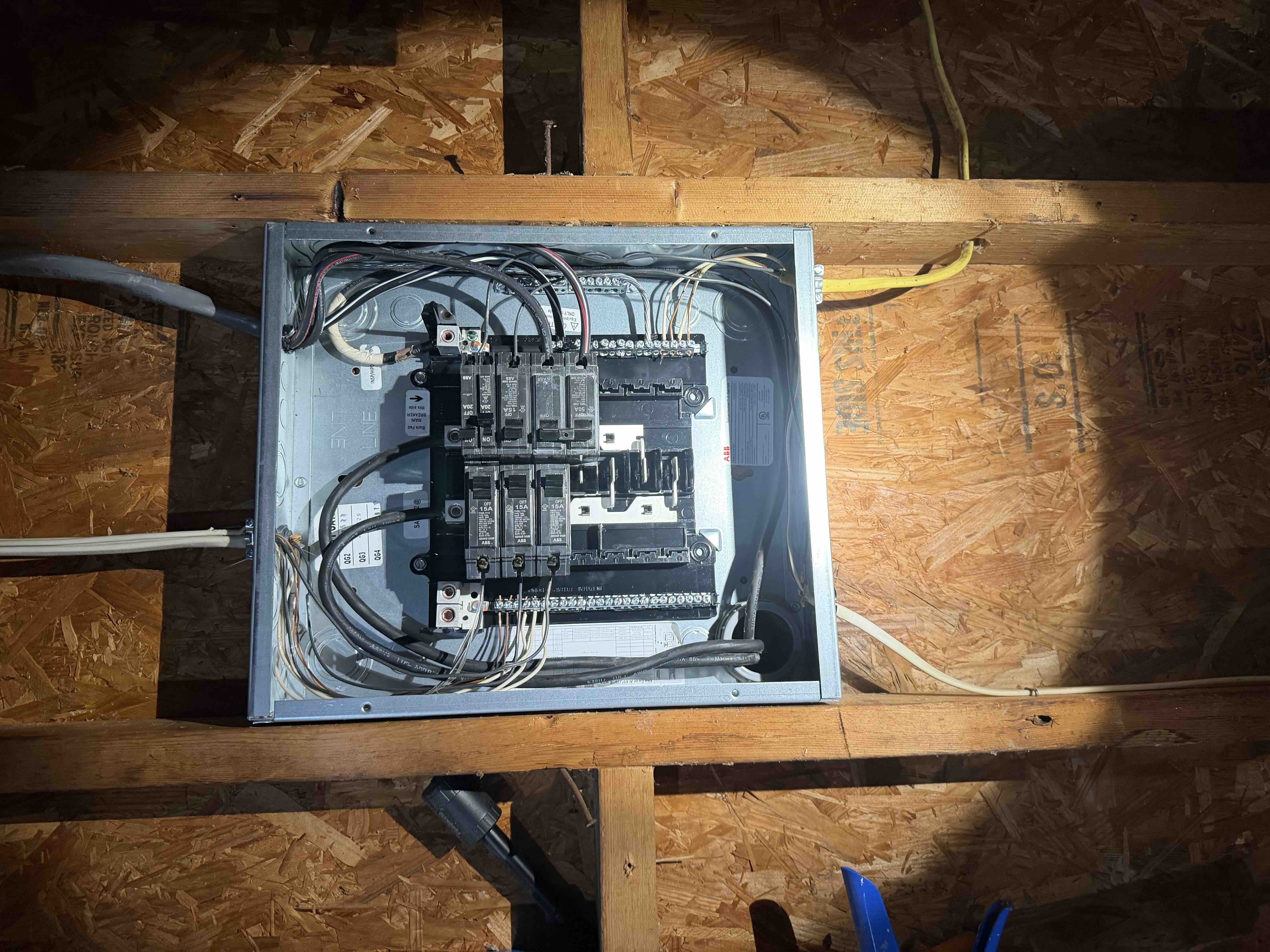 Subpanel interior box mounted between wall framing with organized circuit breakers and neutral bus wiring