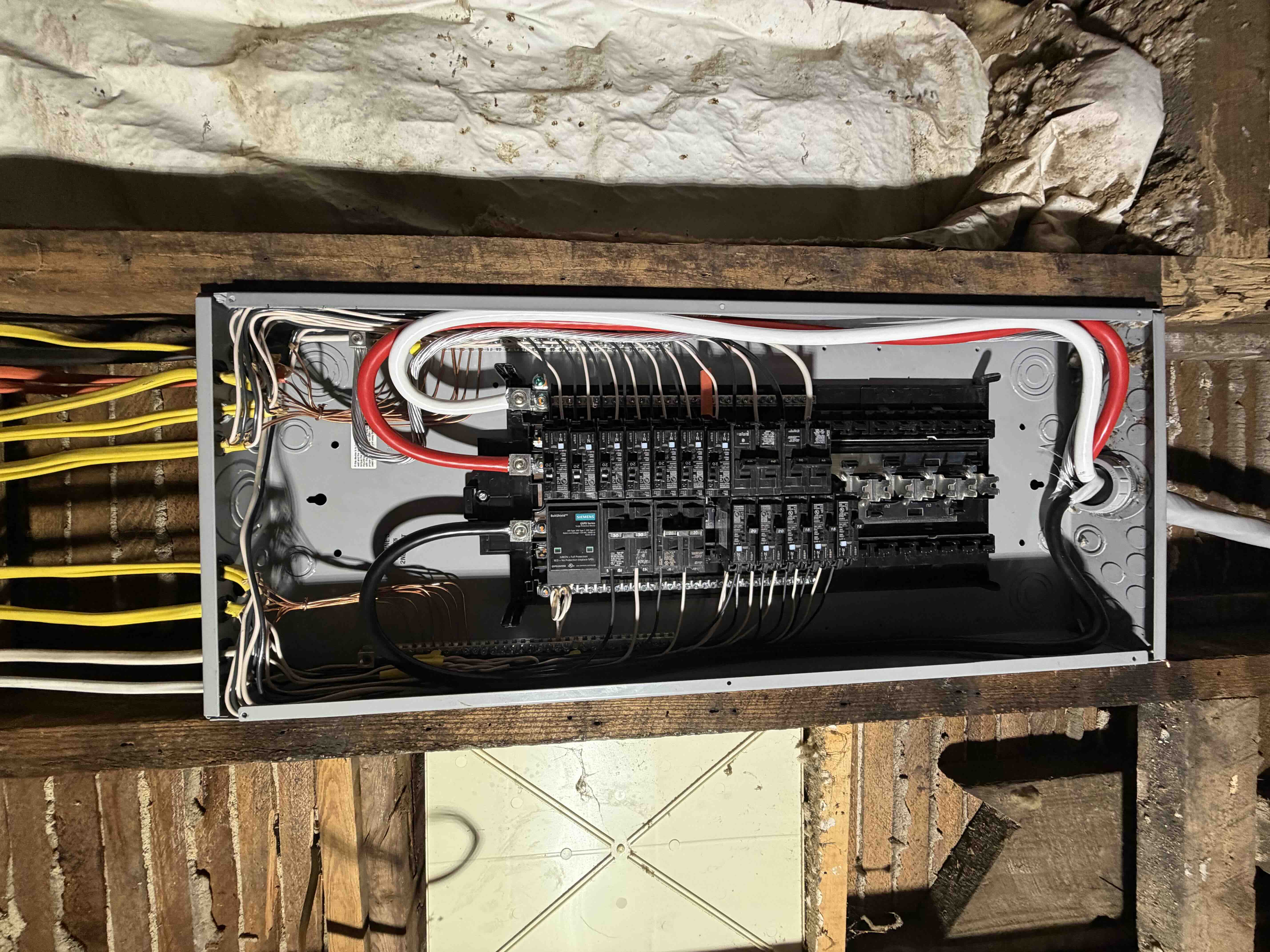 Siemens load center breaker panel installed between wooden ceiling joists with clean branch circuit wiring and main feeder lines