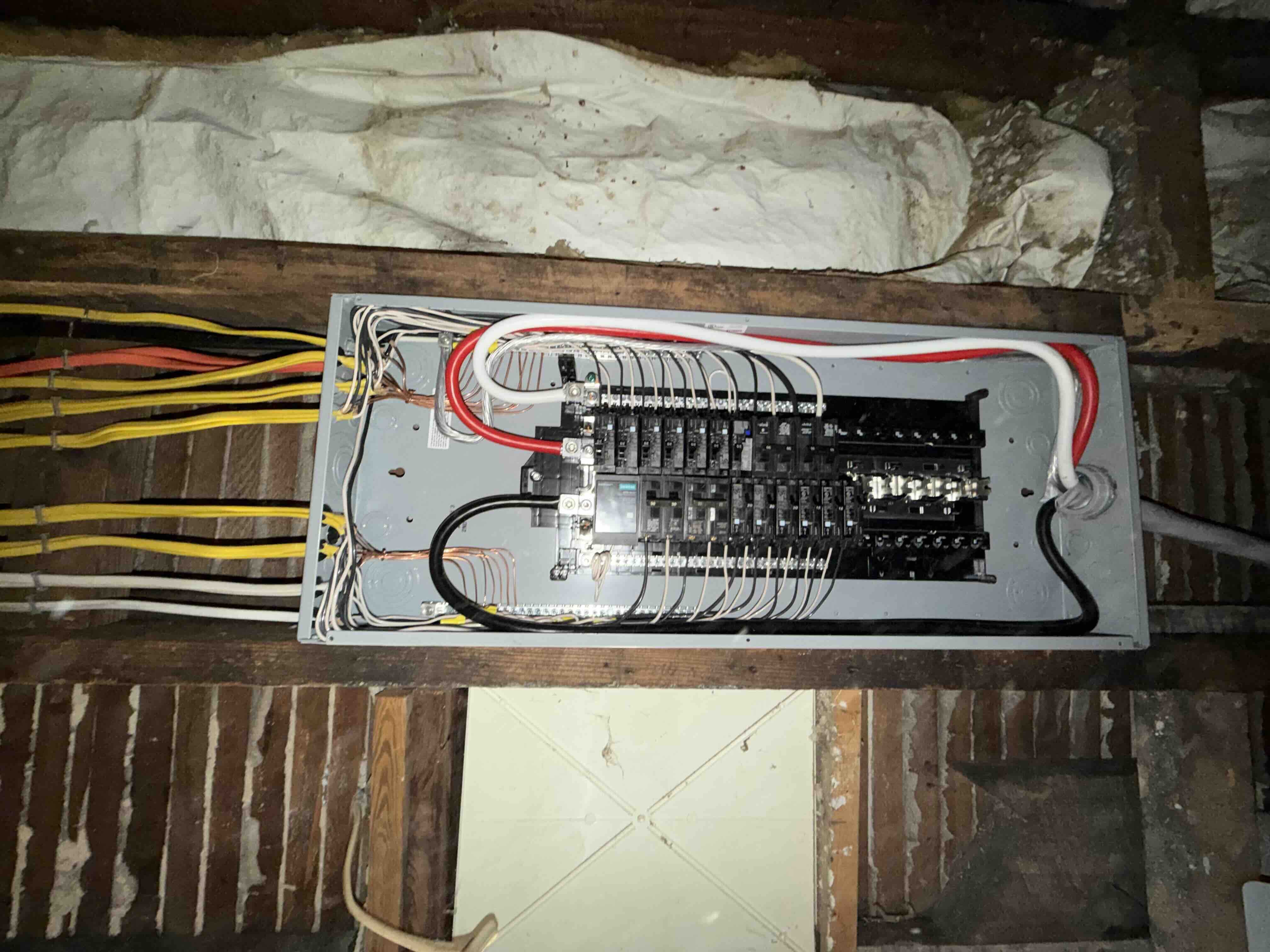 Full interior view of a Siemens breaker panel with circuit breakers, neutral bars, ground wires, and main feeders neatly arranged