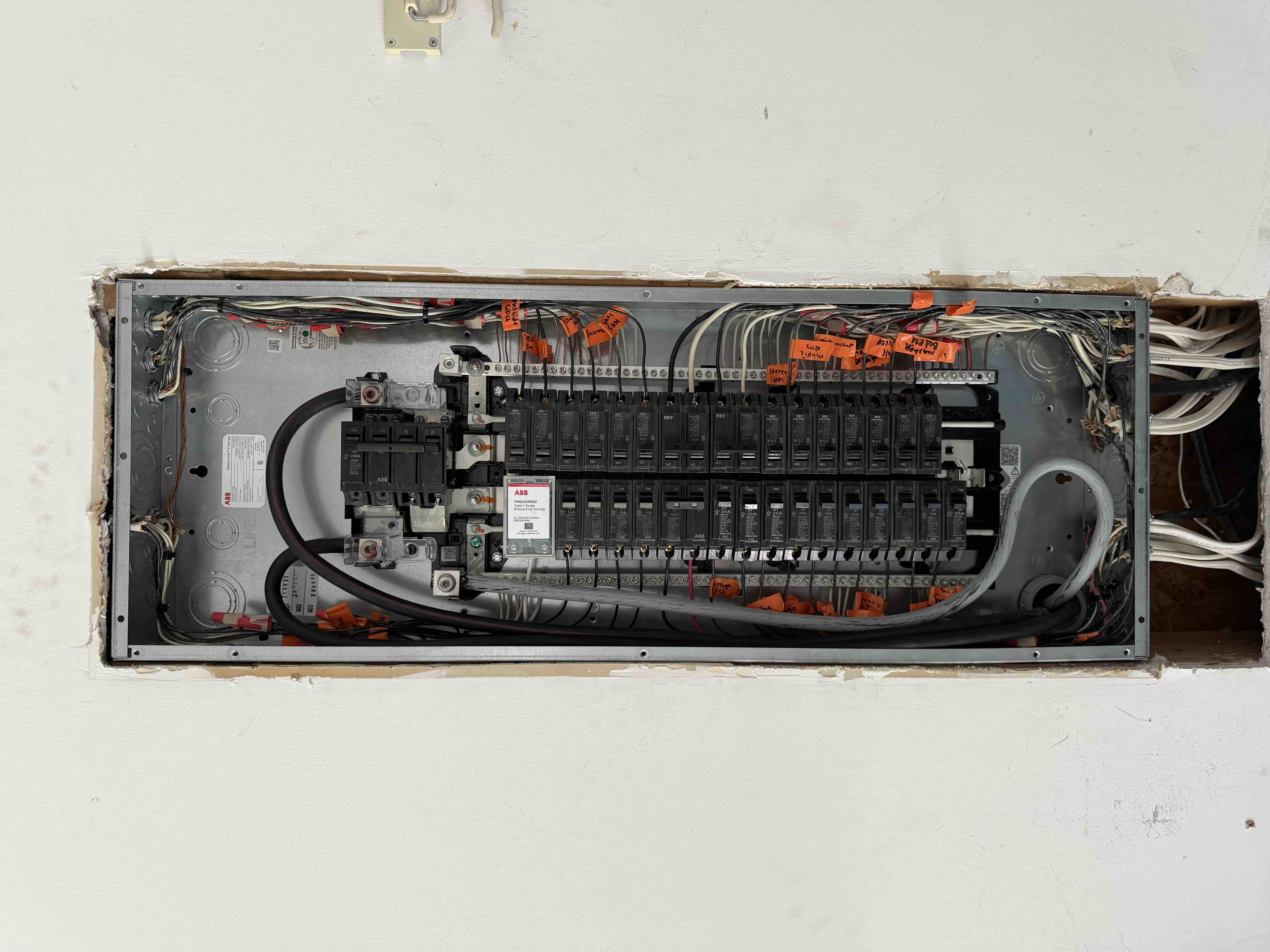 Newly installed ABB breaker panel with a 200 amp main breaker, surge protective device, and every circuit wire tagged in orange