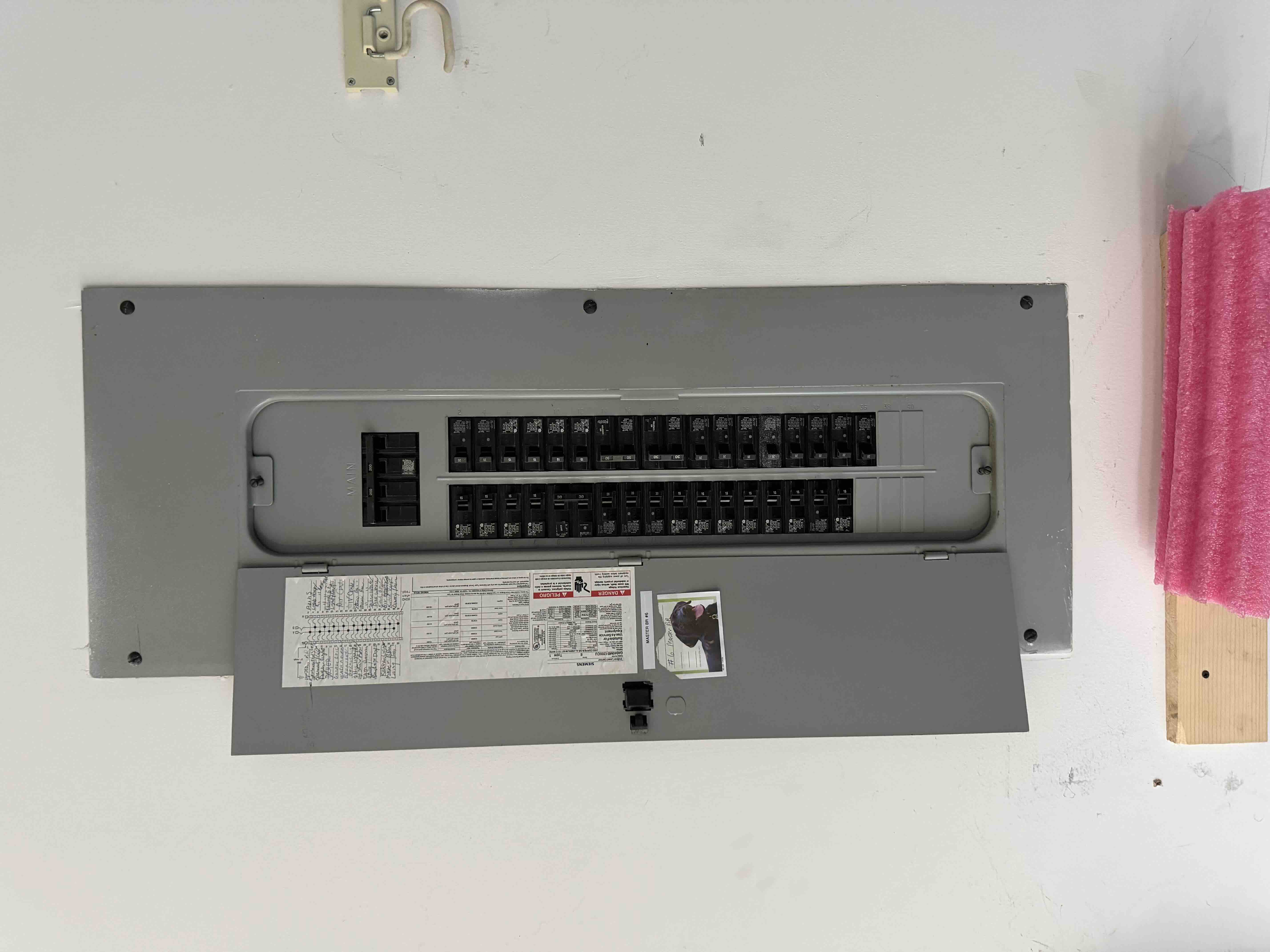 Completed breaker panel installation with the door open, showing a handwritten circuit directory card for homeowner reference