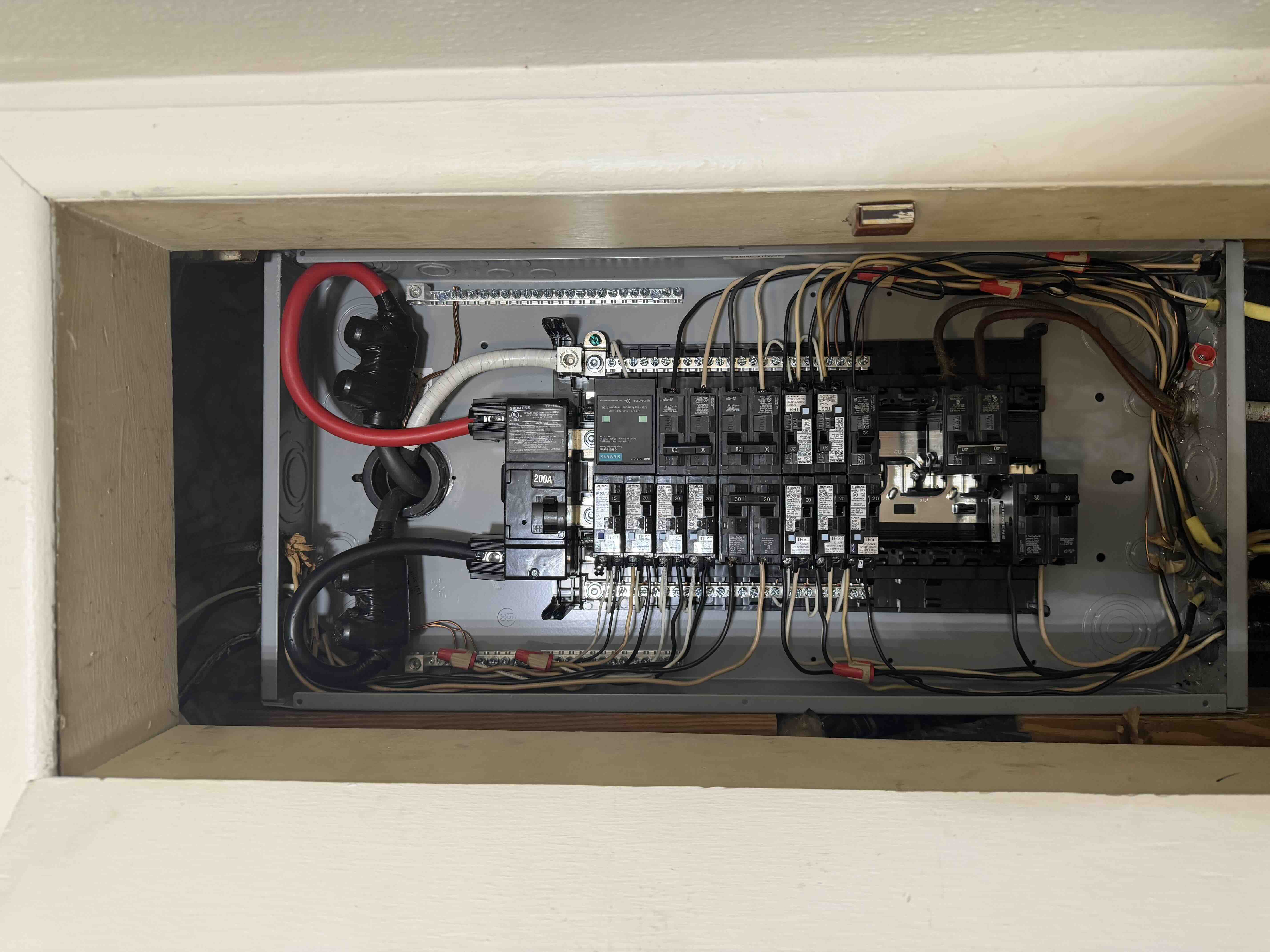 Angled view of the completed Siemens 200 amp breaker panel installation with labeled circuit breakers and neat wiring