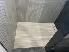 Light wood-look porcelain plank tile floor installation with linear drain by Level 4 Tile and Stone San Diego