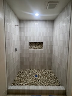 Gray vertical plank tile shower with river pebble floor and decorative mosaic niche by Level 4 Tile and Stone San Diego